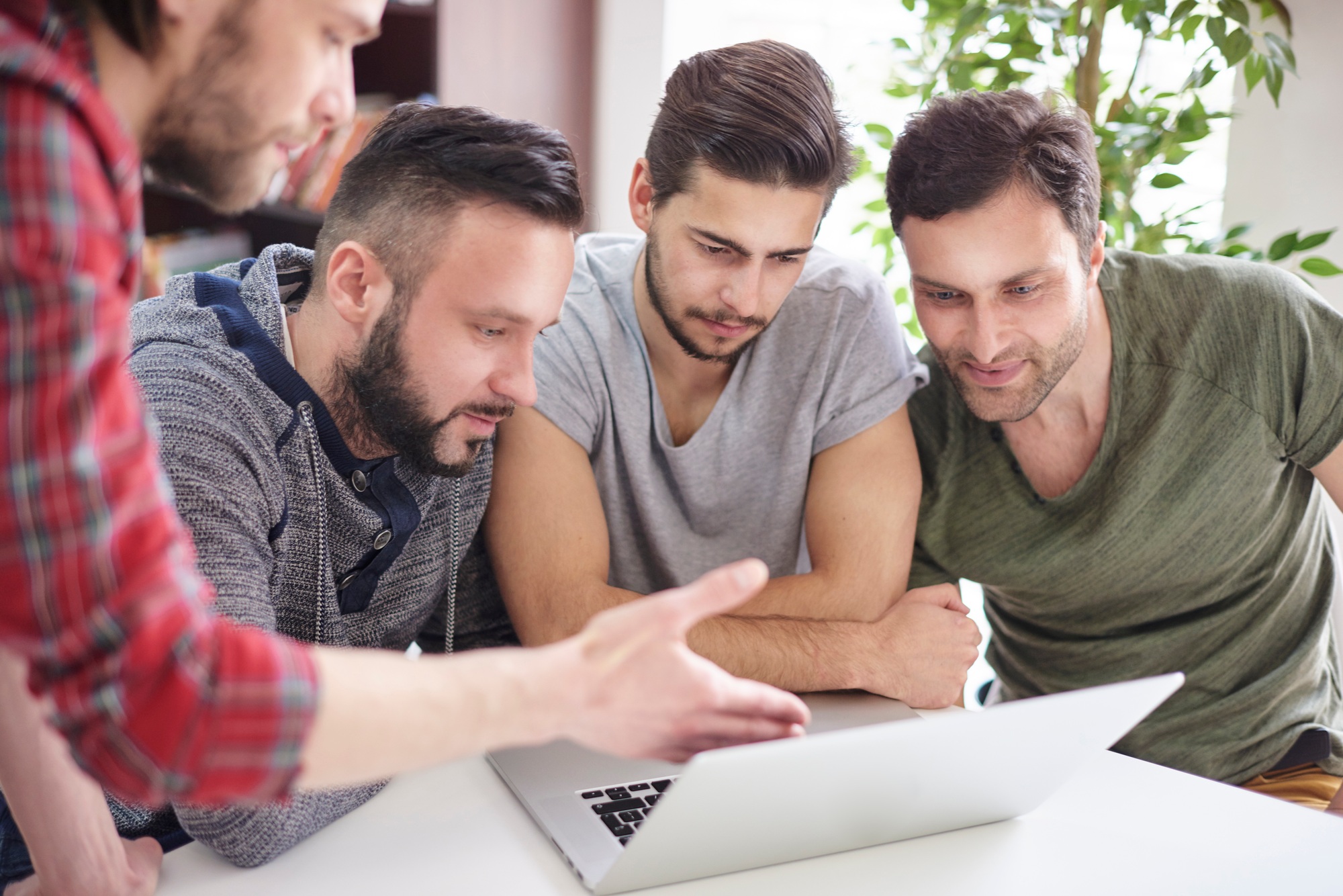 Focused group of men sitting in front of the laptop