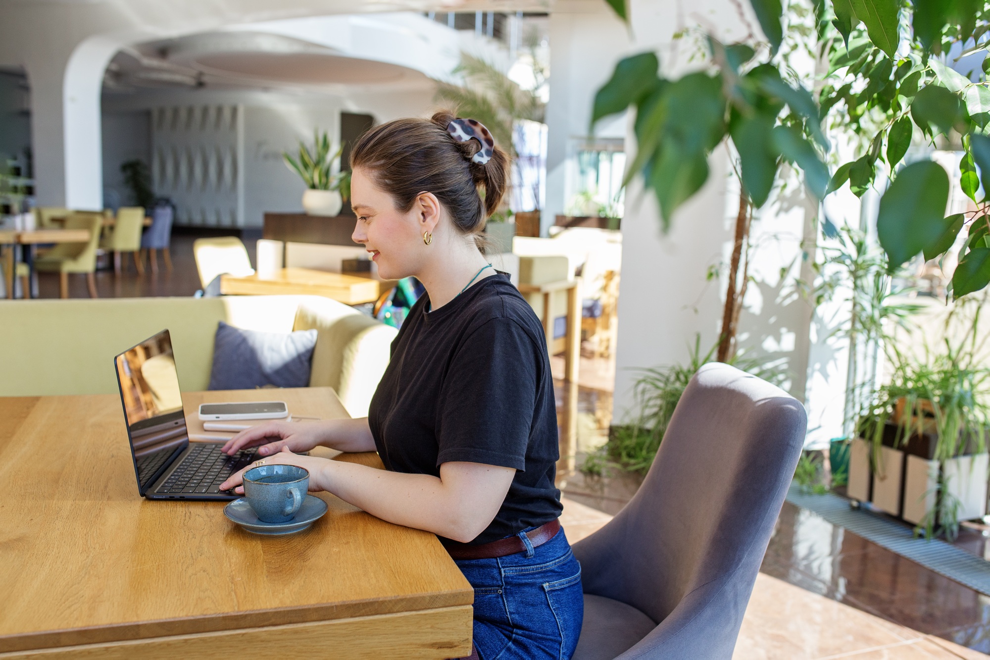 Freelancer Using Laptop in Bright Modern Cafe