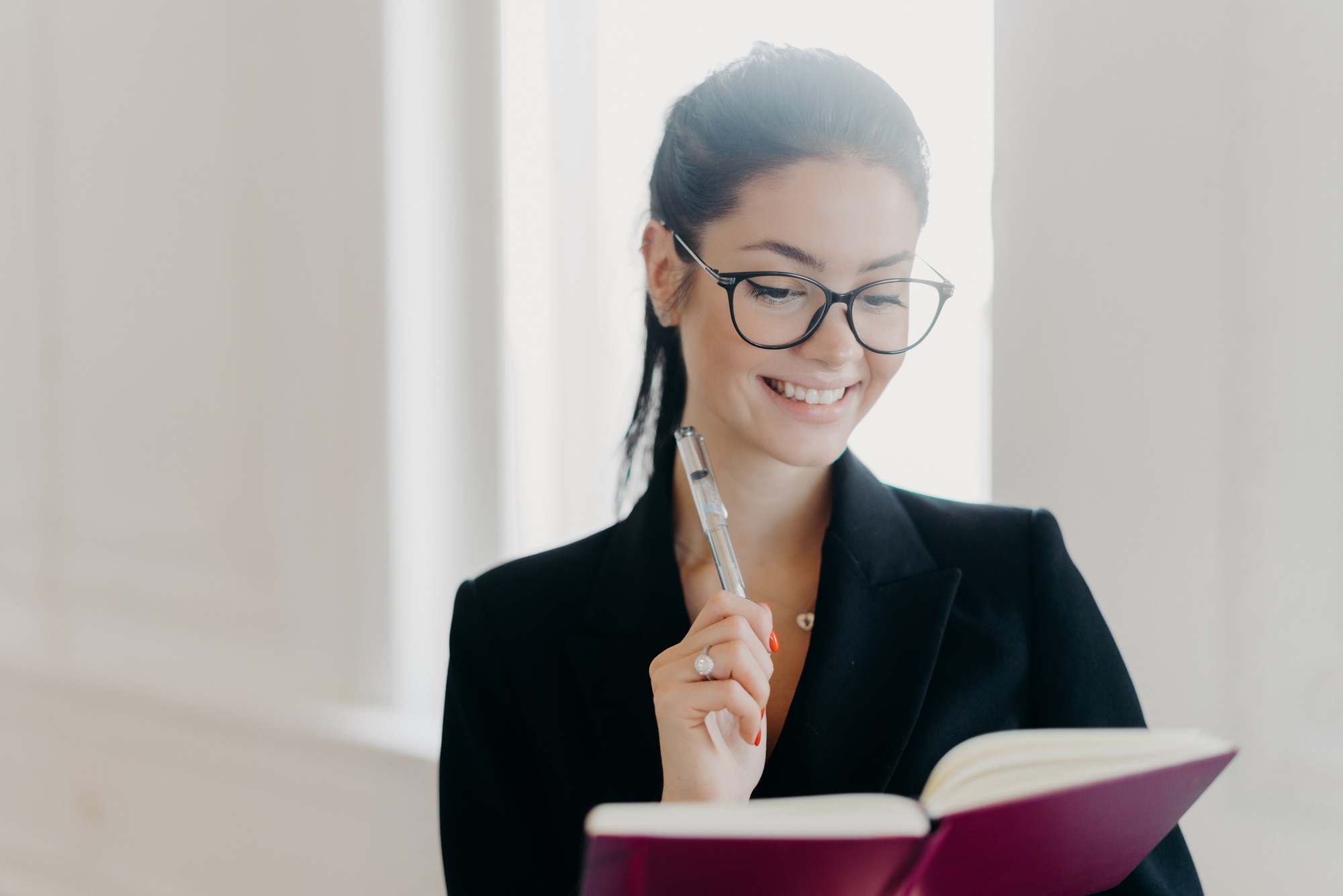 Glad prosperous woman CEO writes in notepad, plans her work schedule