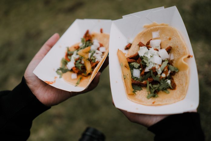 Hands holding Mexican street tacos in restaurant gray eating outdoors cultural food