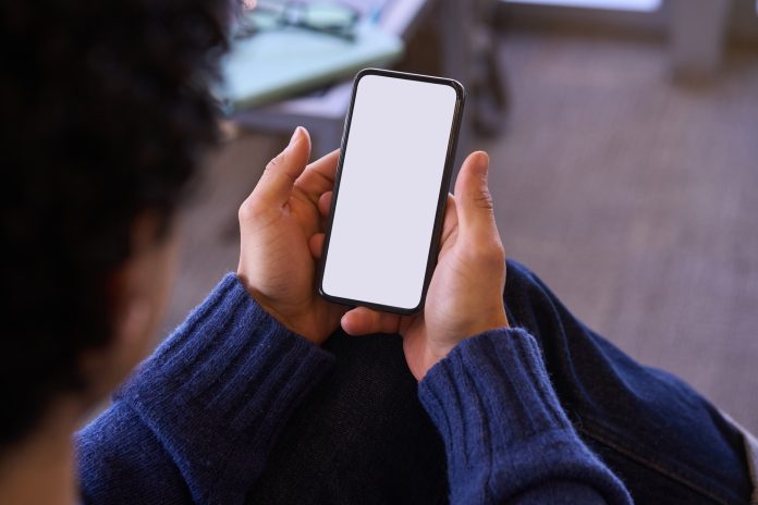 Hands holding modern smartphone. Blank white digital screen for graphic display. Mockup. Ad space