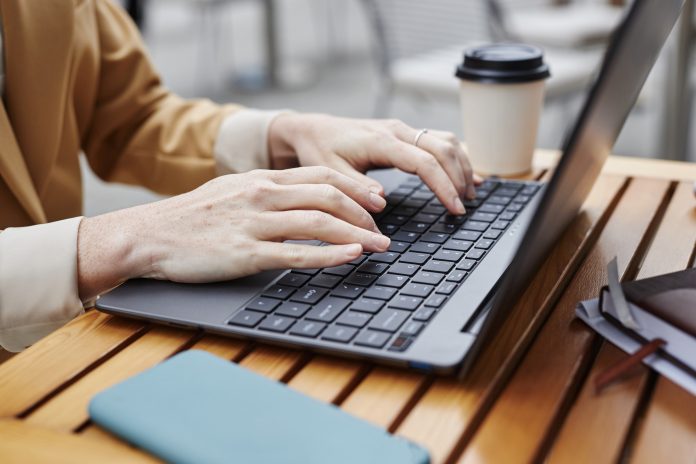 Hands of young businesswoman or solopreneur typing on laptop keyboard