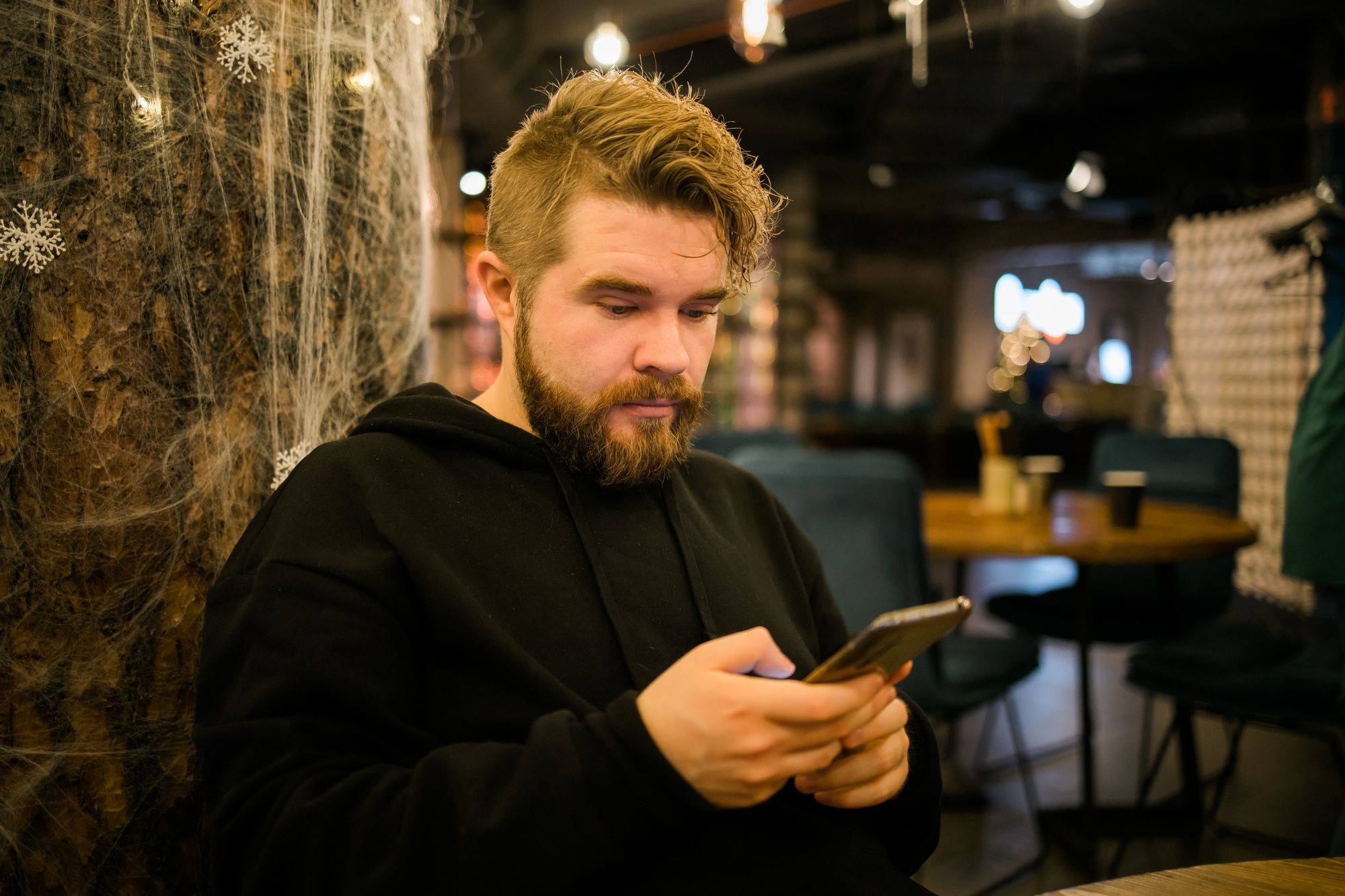 Handsome concentrated guy making money transaction via application on mobile phone with 4g internet