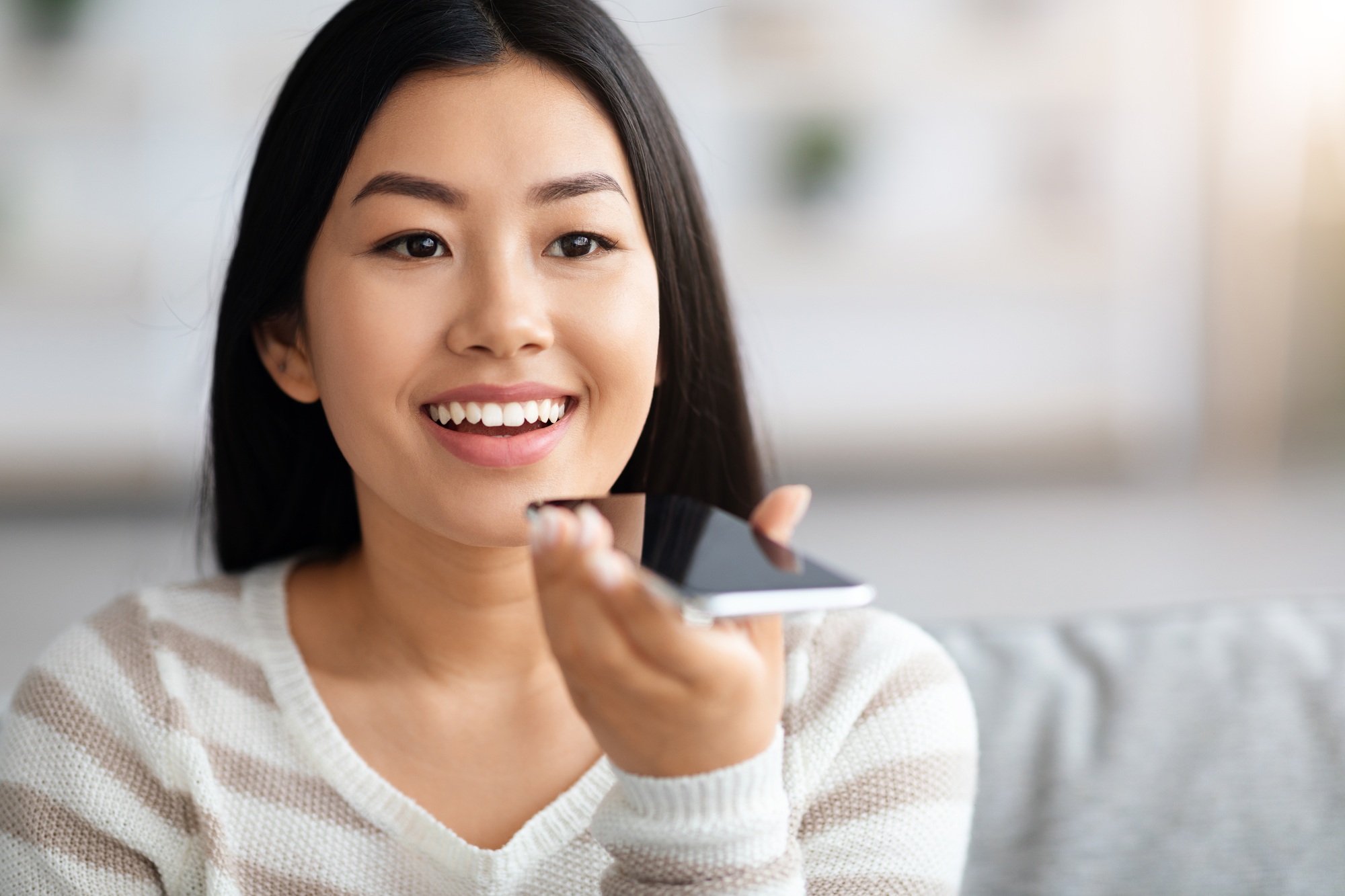 Happy Asian Lady Using Virtual Voice Assistant On Smartphone At Home