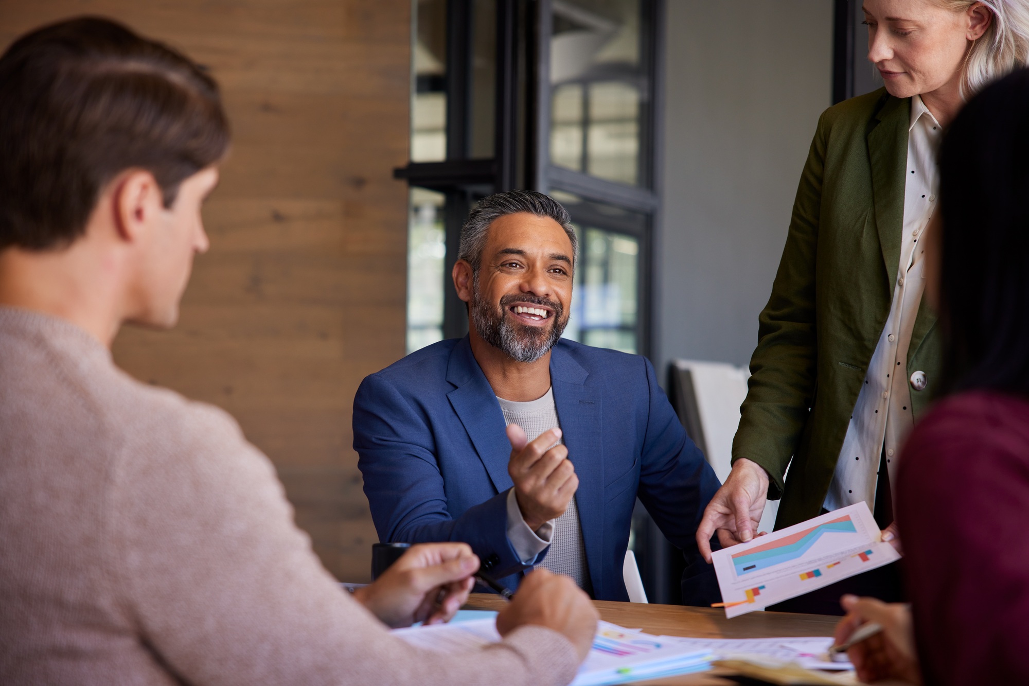 Happy businessman smiling while discussing sales with his team