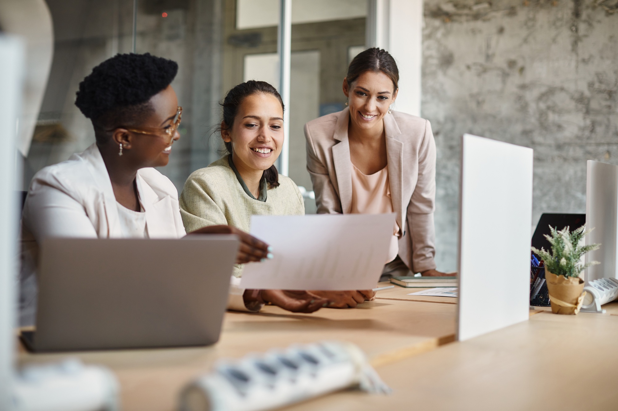 Happy female entrepreneurs cooperating while analyzing business plans in the office.