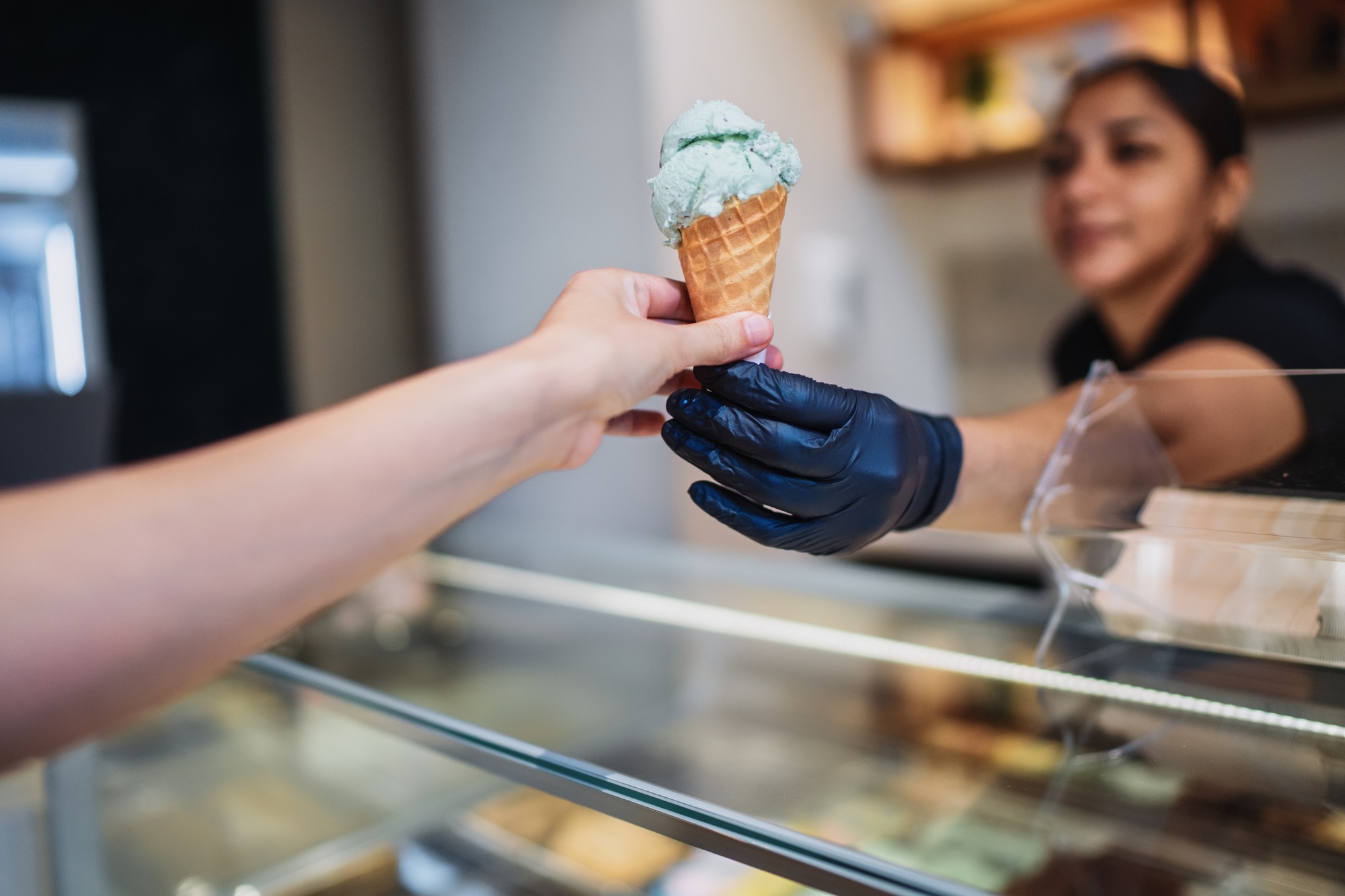 Ice cream seller giving pistachio ice cream cone to customer