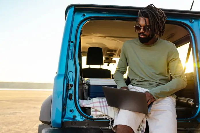 Image of african american man using laptop while travelling with car