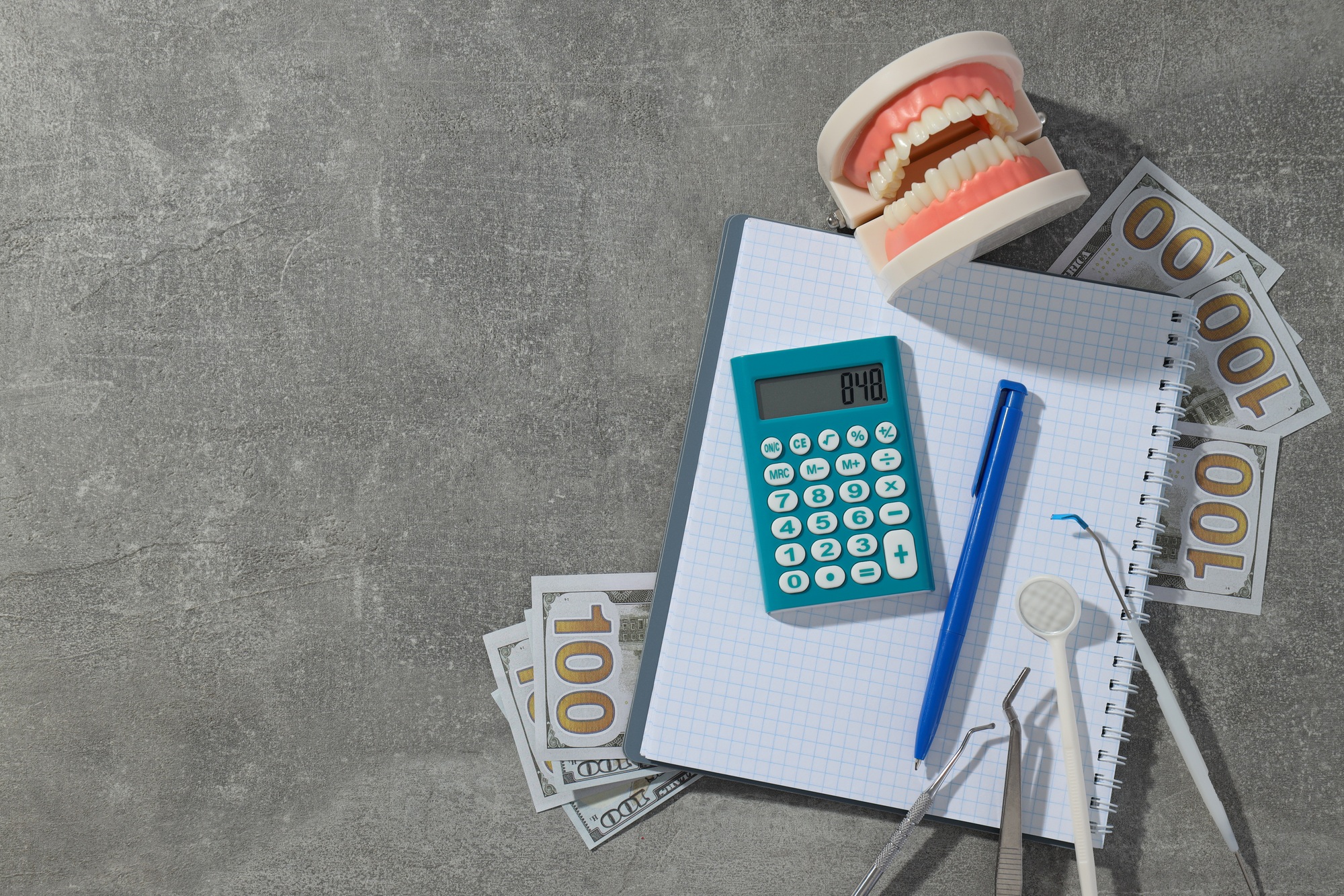 Jaw and dental instruments, calculator, cash and notepad on gray background, space for text