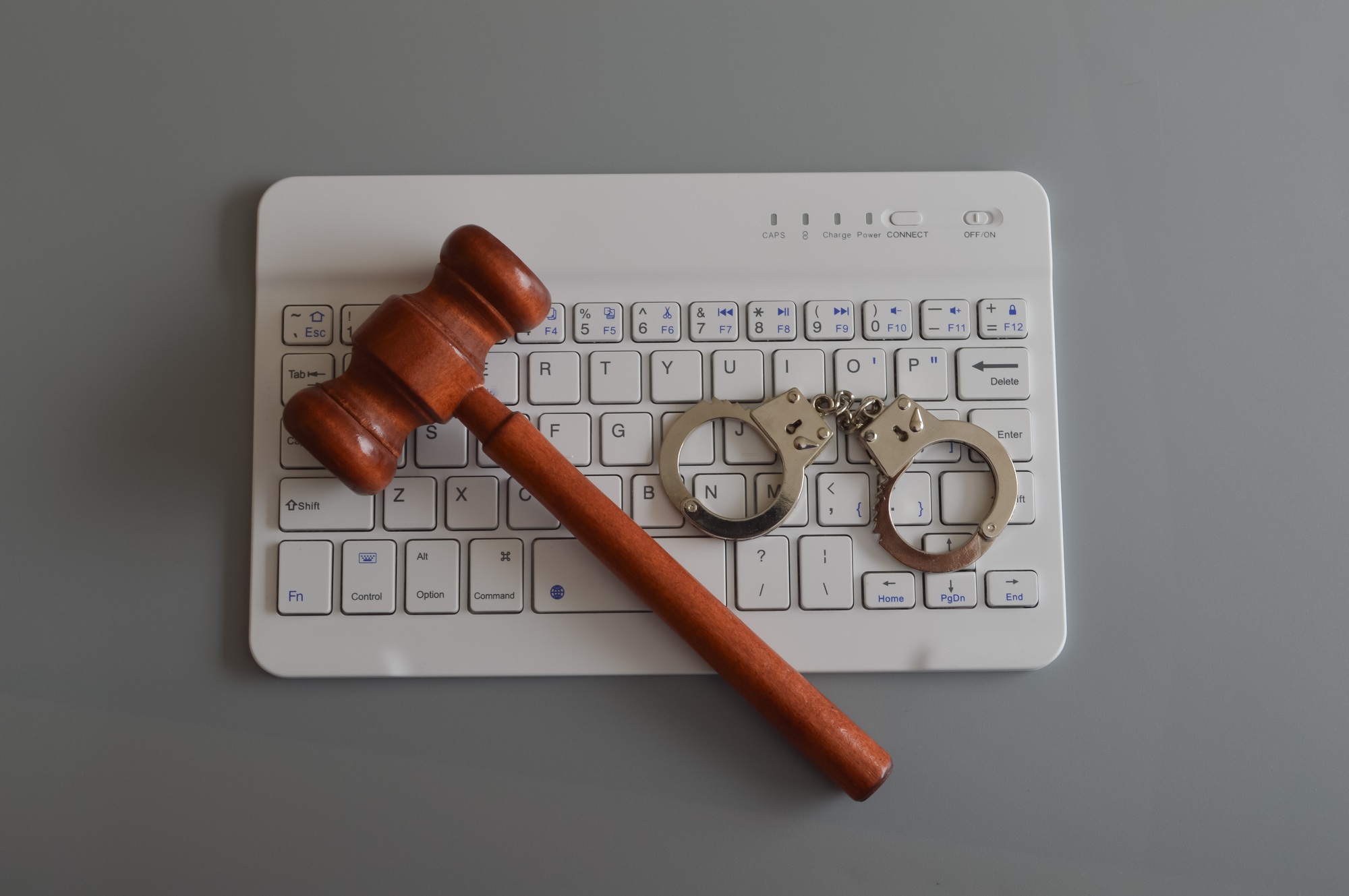 Judge gavel, laptop keyboard and handcuffs. Online scam, fraud, arrest and criminal concept.