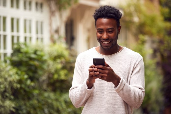 Male Vlogger Or Social Influencer In City Using Mobile Phone On Street To Post To Social Media