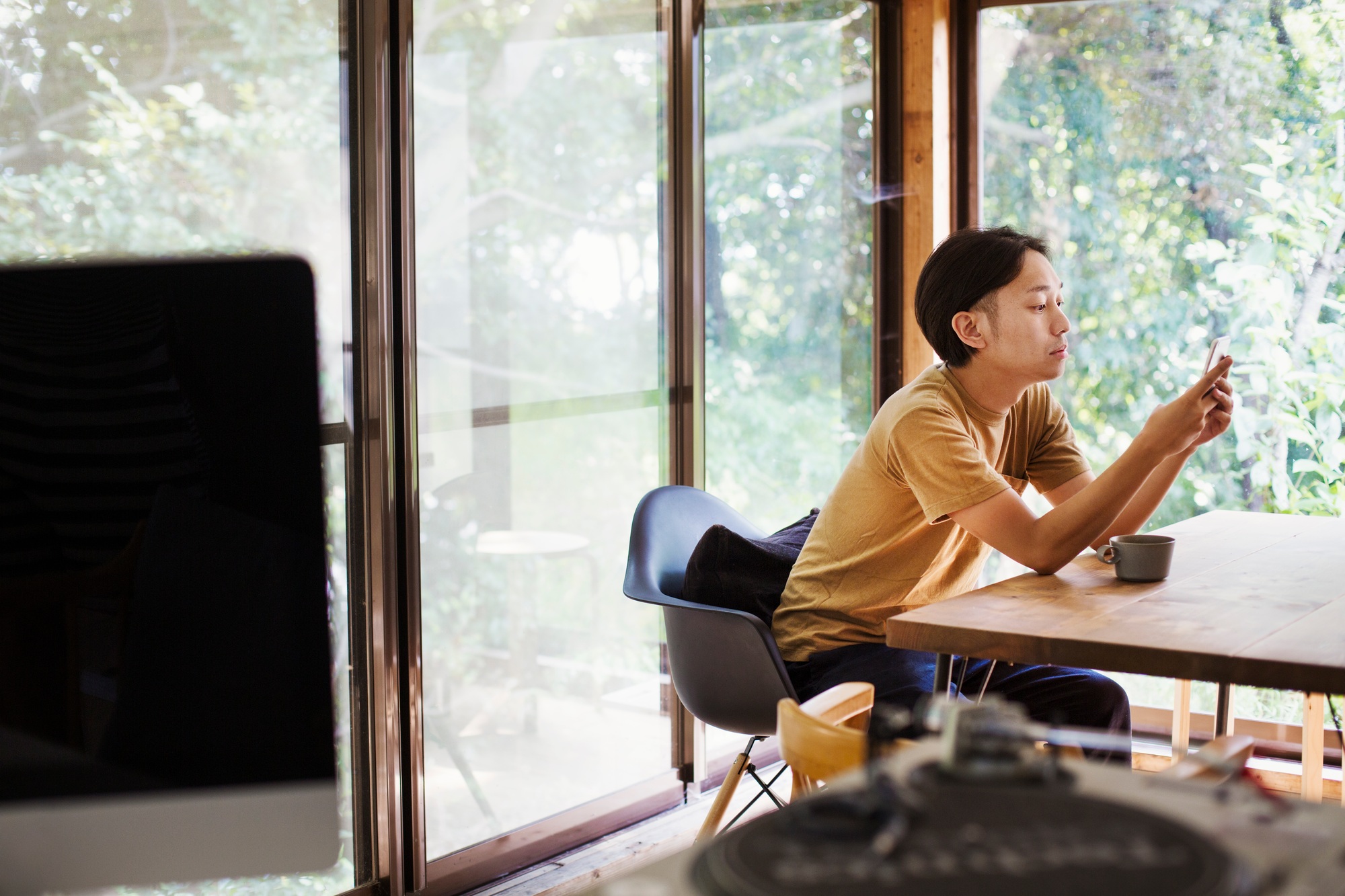 Man sitting indoors at table, looking at mobile phone.