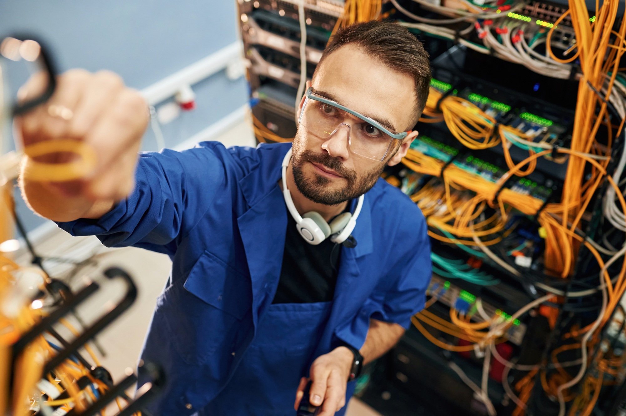 management of cables. Young man is working with internet equipment and wires in server room