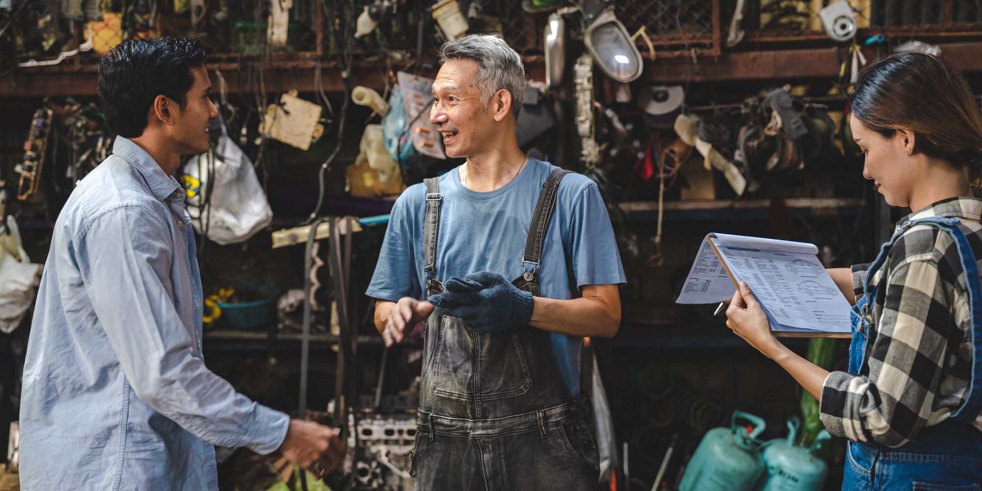 mechanic technician in uniform reading or writing document and standing in auto repair garage