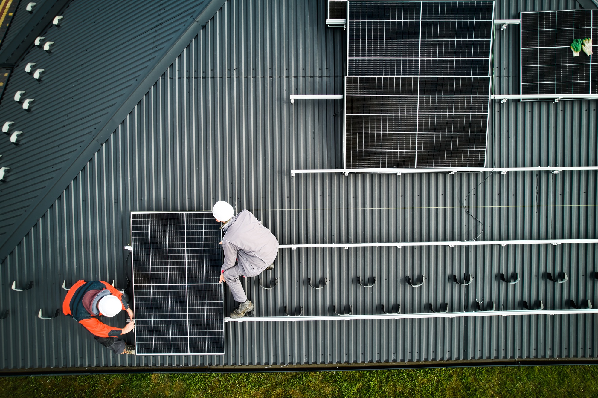 Men workers installing solar panels on roof of house.