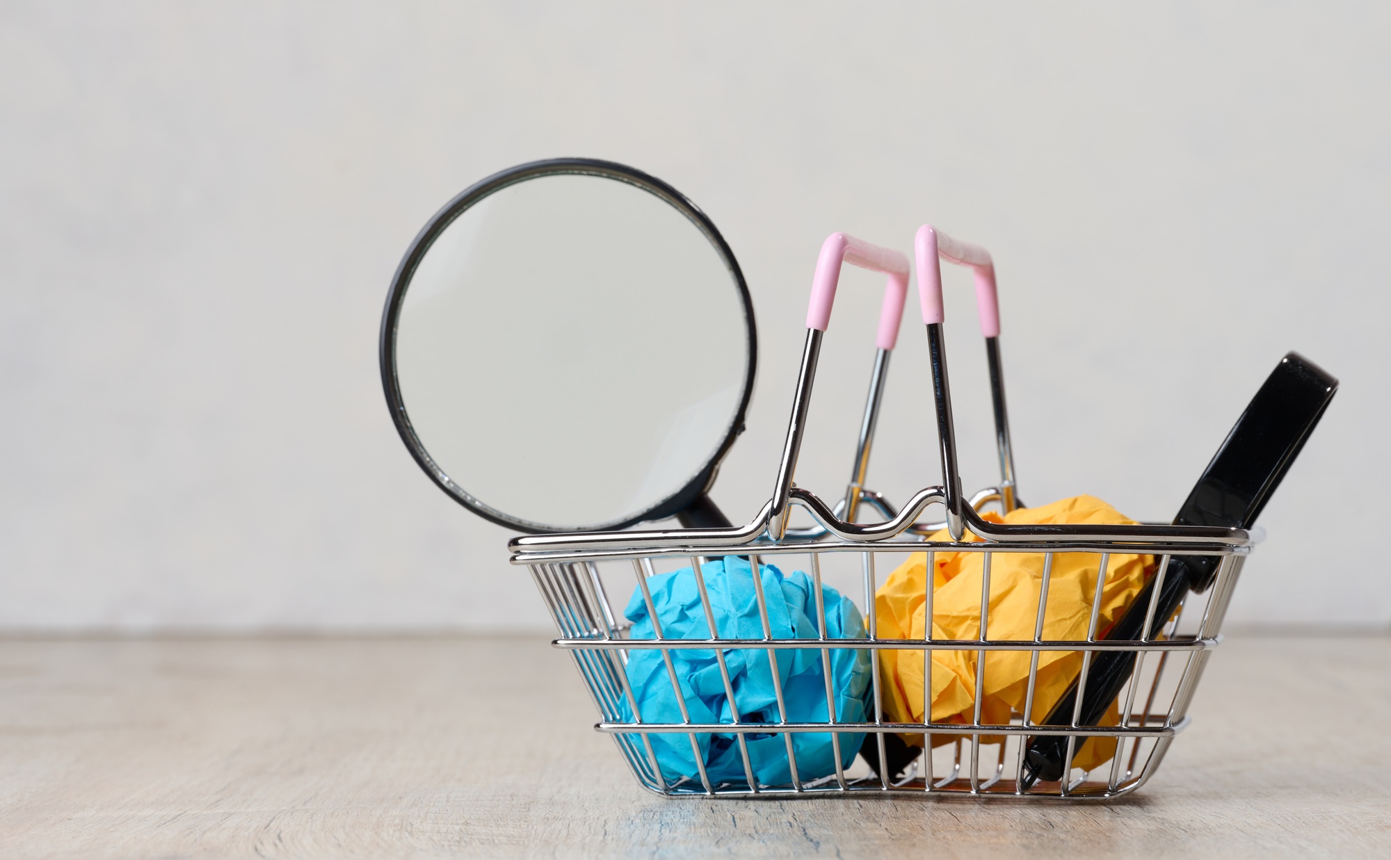Miniature shopping basket and magnifying glass. Purchasing power concept