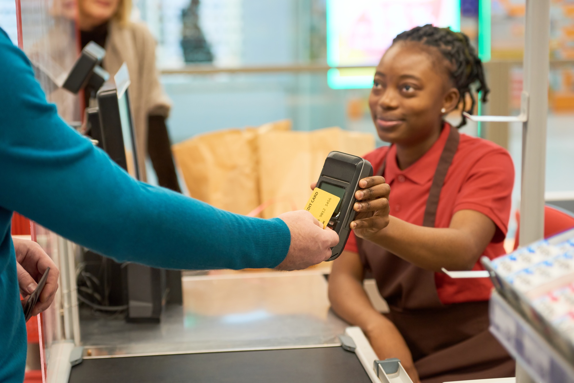 Modern man paying for goods by credit card while holding it by payment terminal