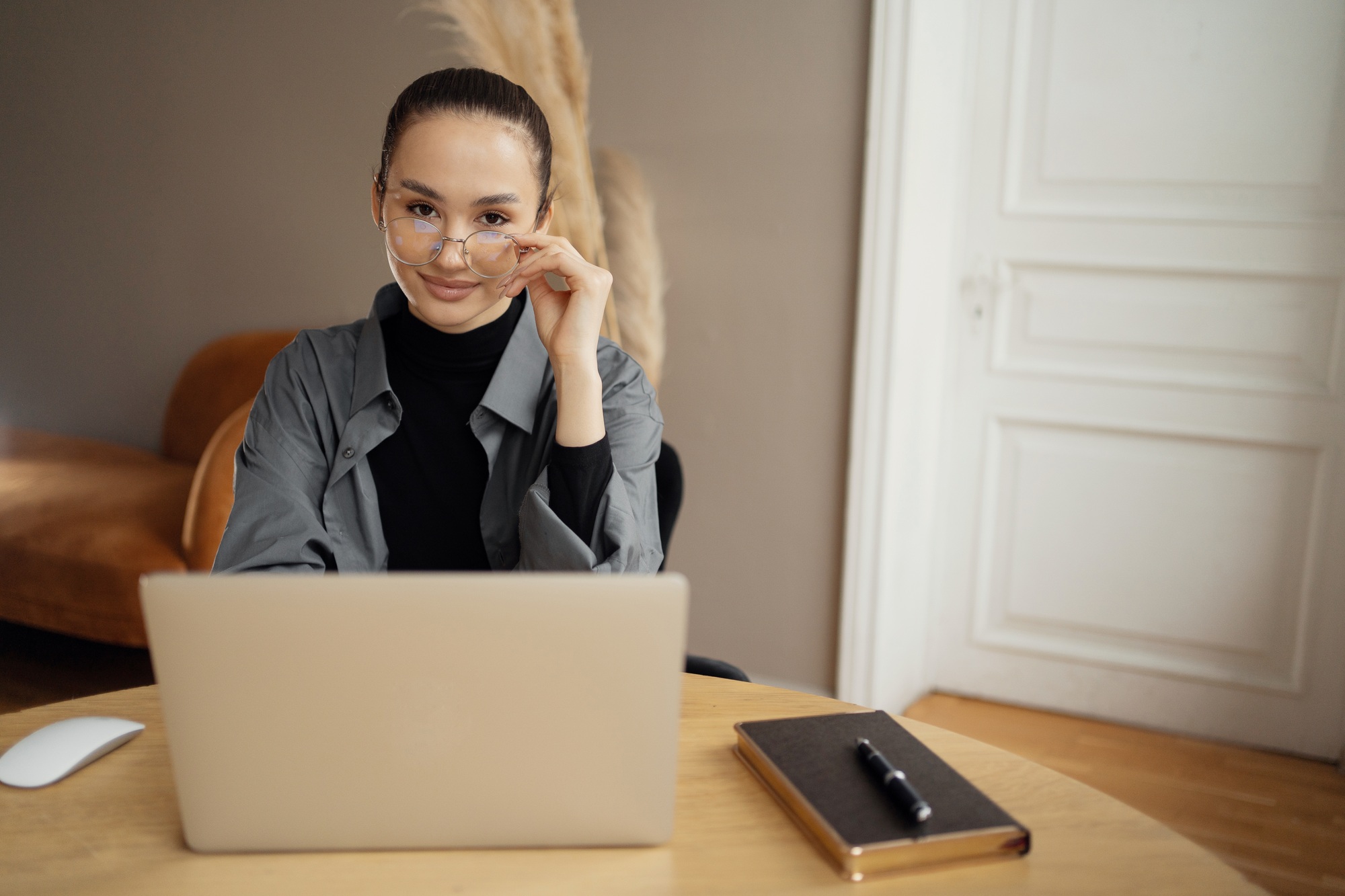 Modern professional with glasses working at laptop in a minimalist setup.