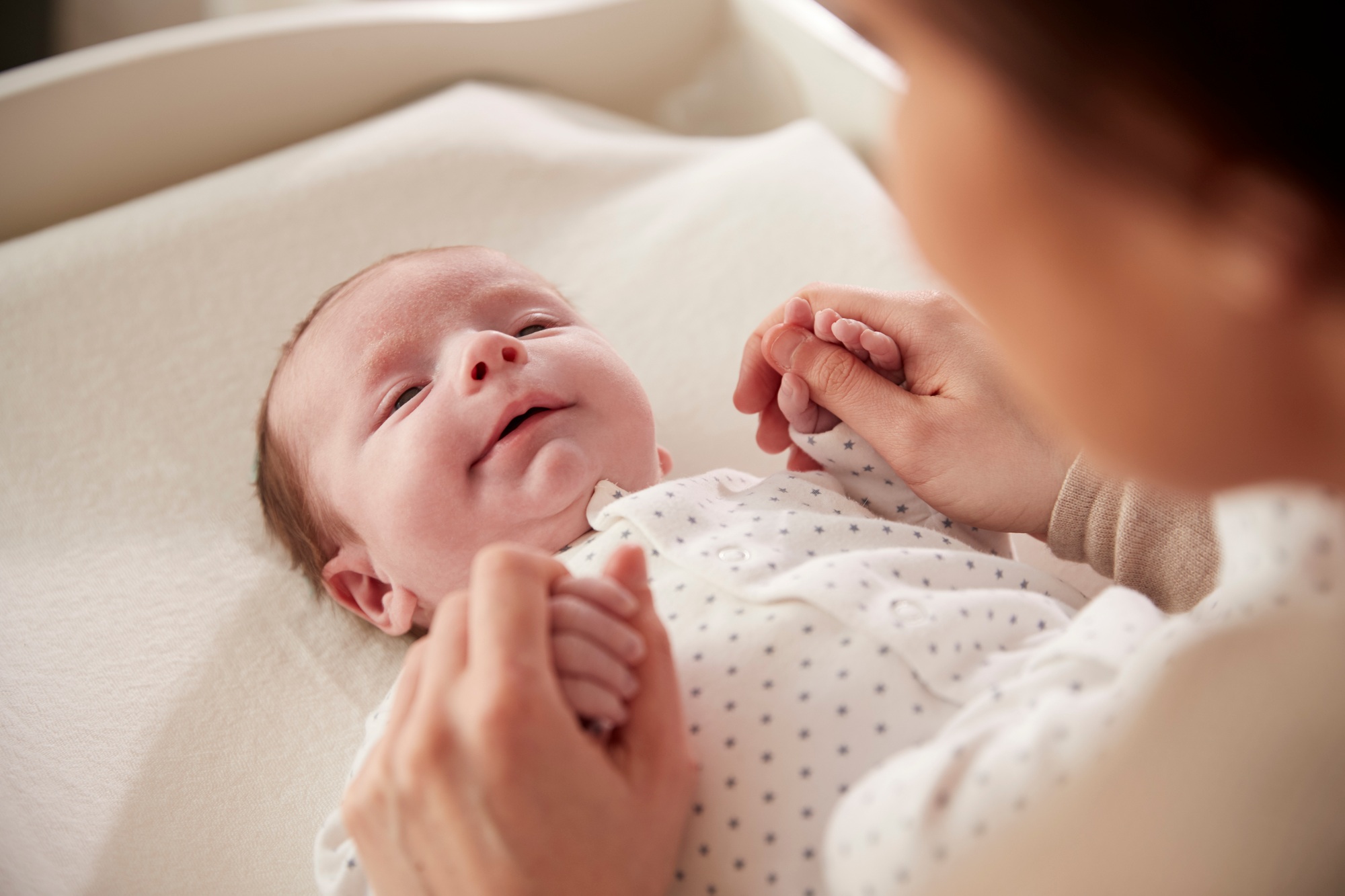 Mother Playing With Newborn Baby Lying On Changing Table