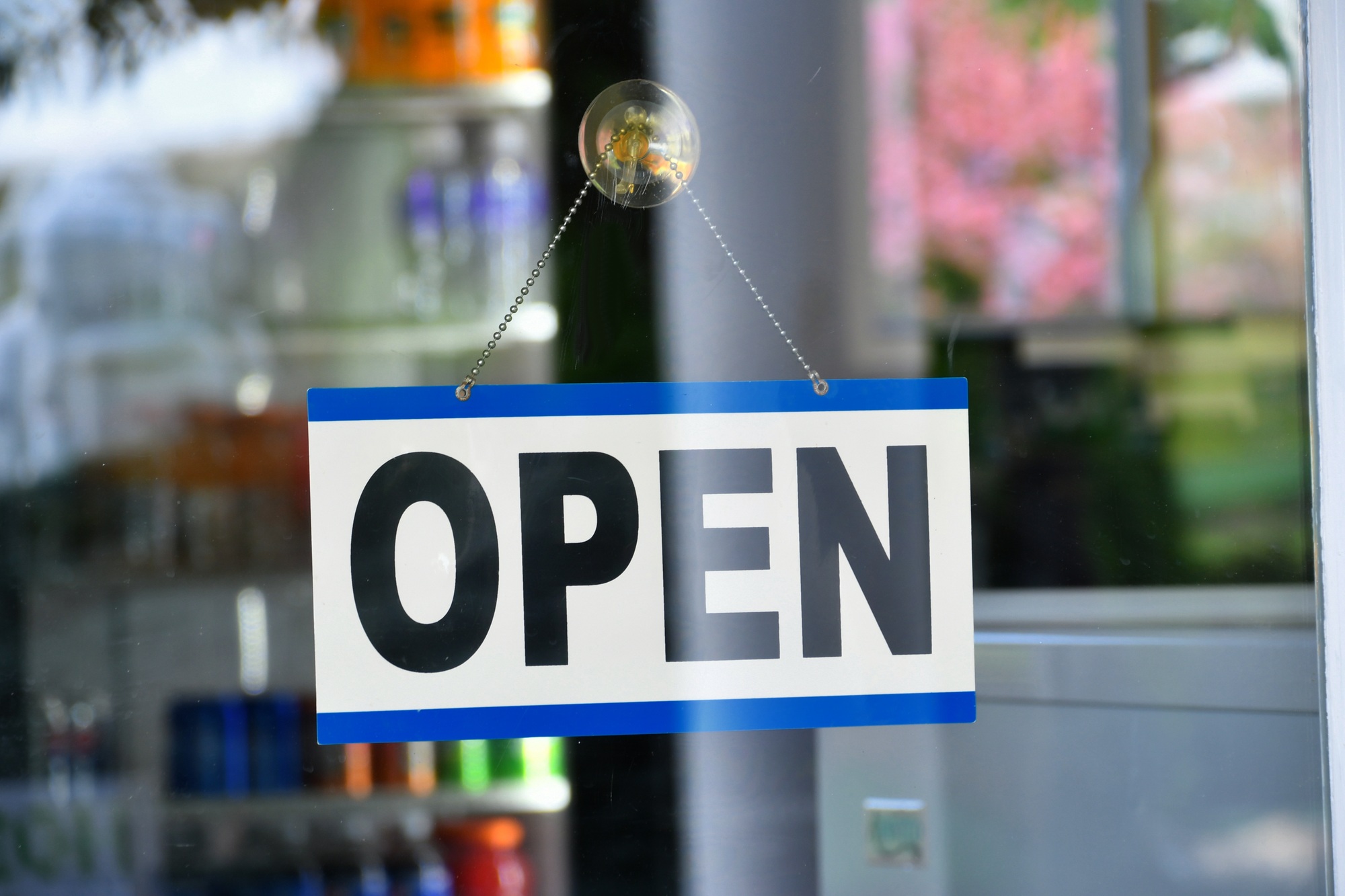Open sign hanging on a shop's door window - Yes, we're open for business