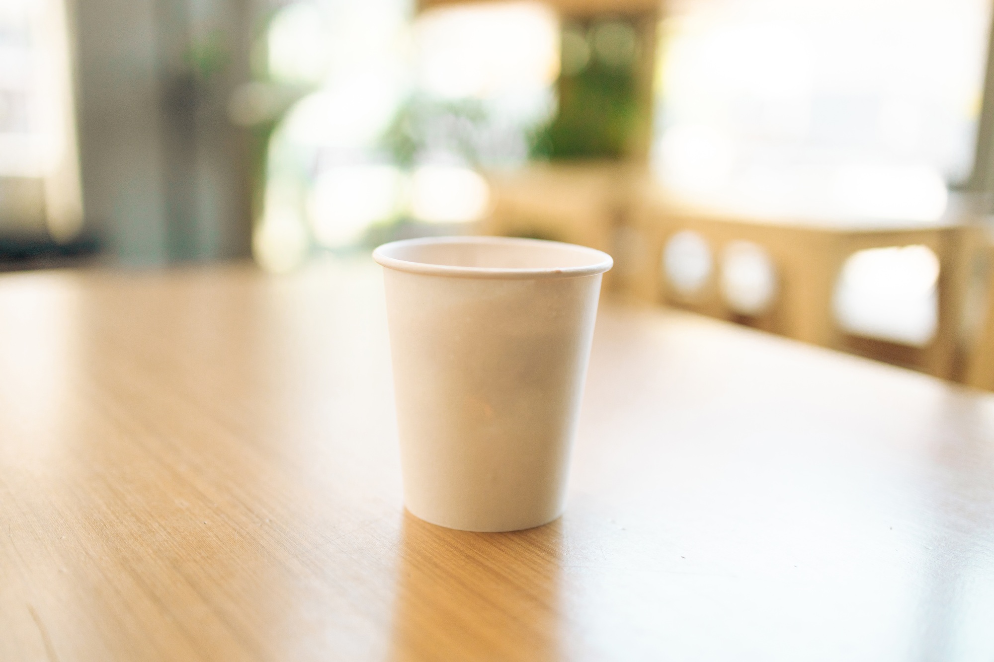 Paper coffee cup on a wood table in coffee shop.