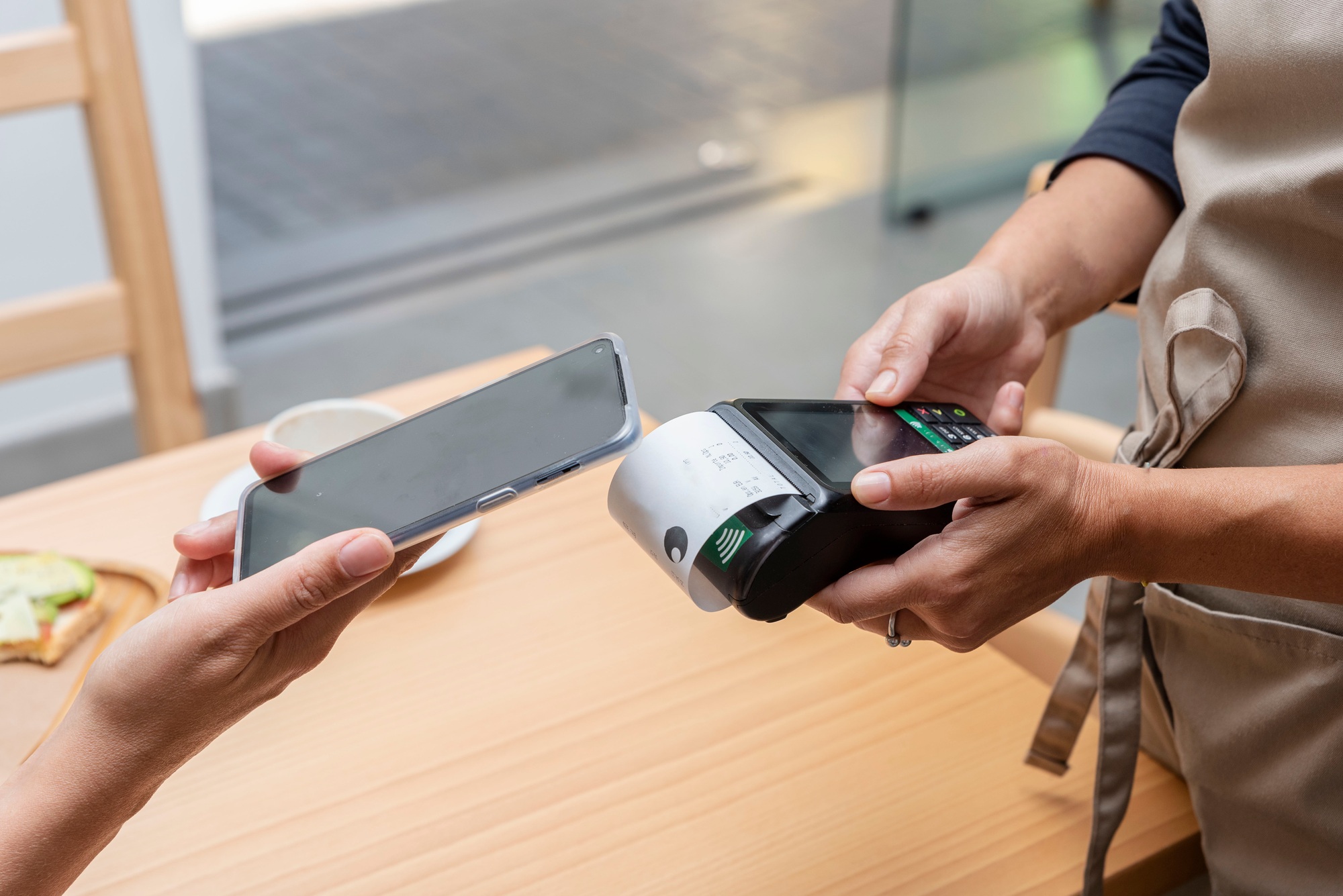 paying with a mobile app through a payment terminal in the hands of the waitress in a bar