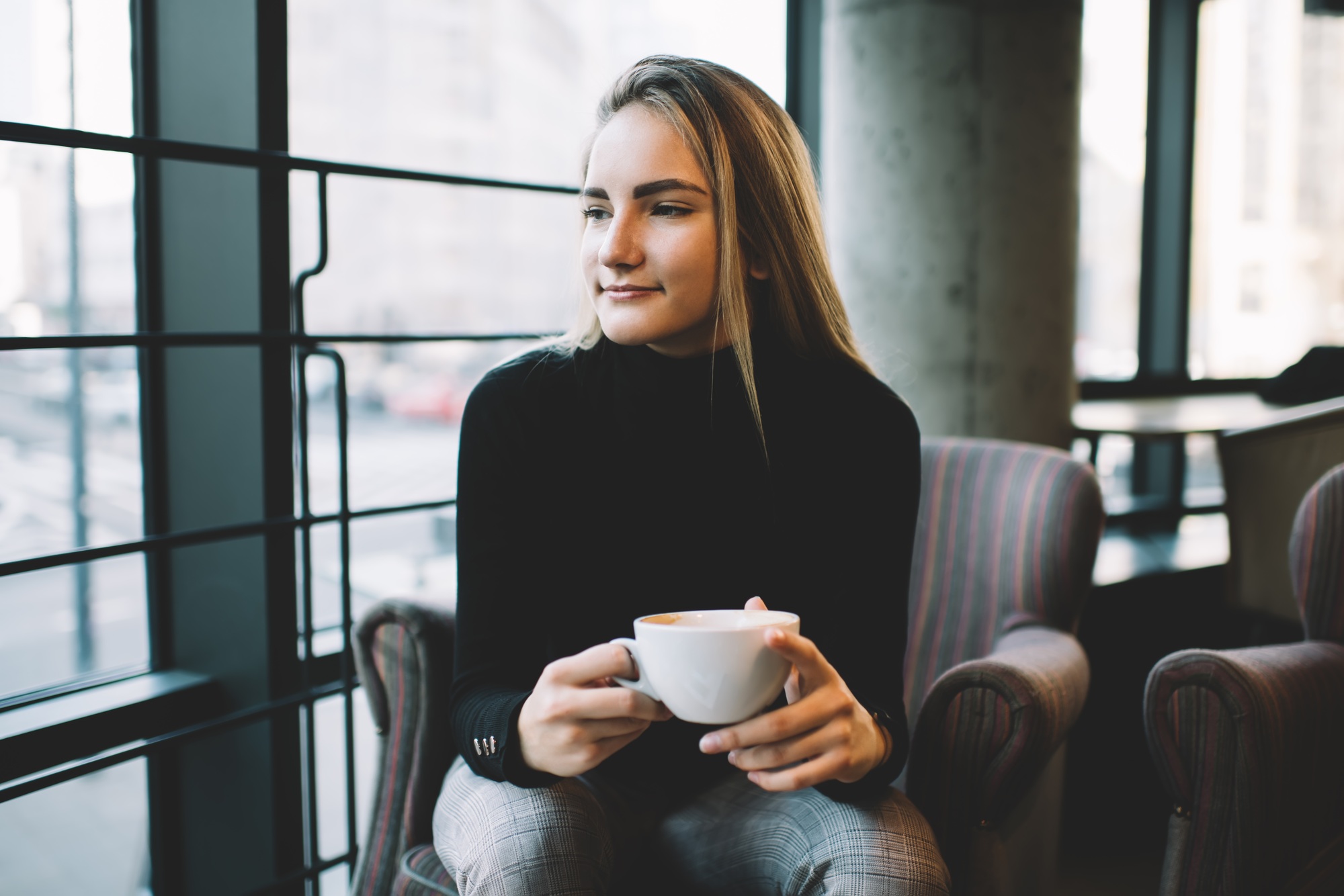 Pensive Caucasian customer with cup of hot tea feeling pondering in cafeteria