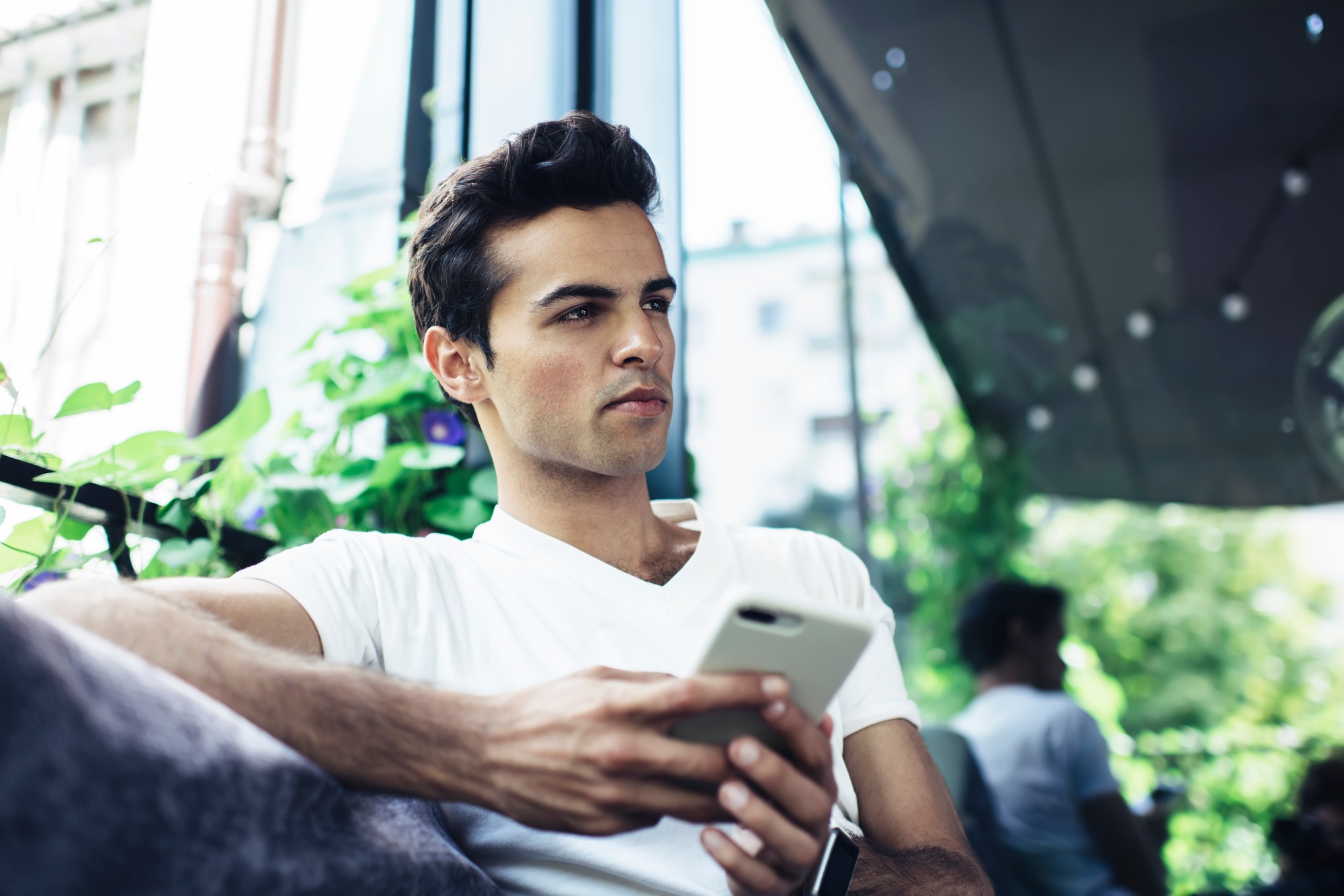 Pondering male with smartphone device thinking about idea for network content
