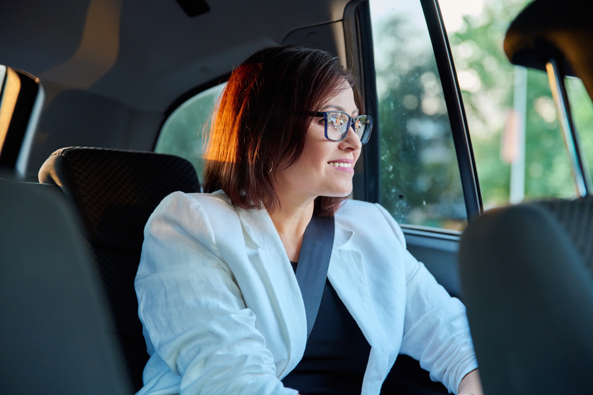 Portrait of business elegant middle-aged woman in car in back passenger seat