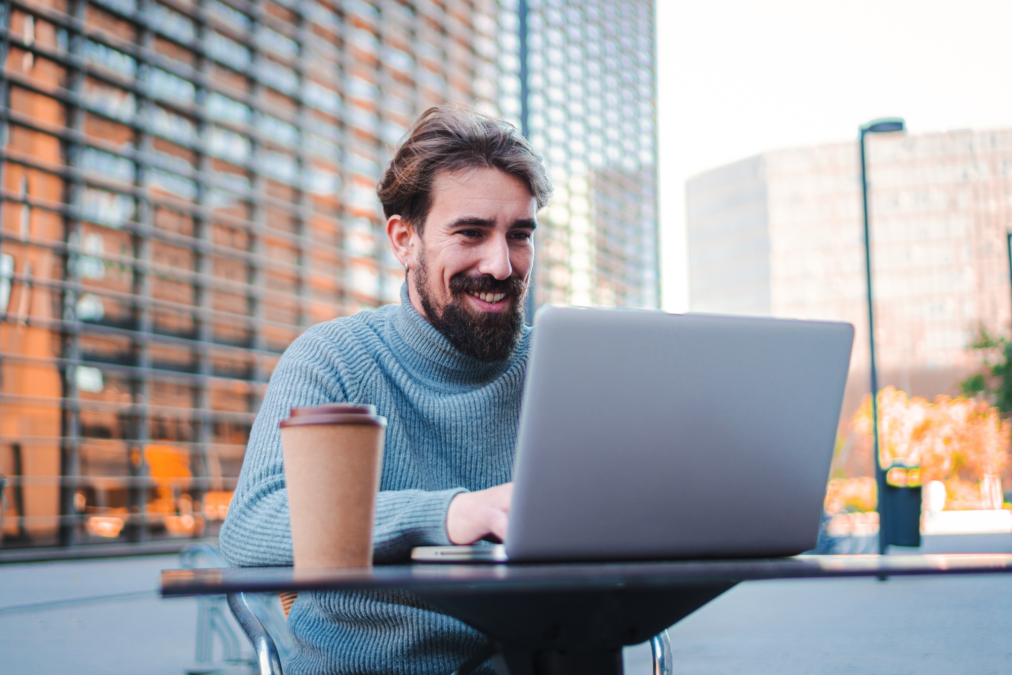 Portrait of young male remote working from coffee terrace and having work confrence video call with