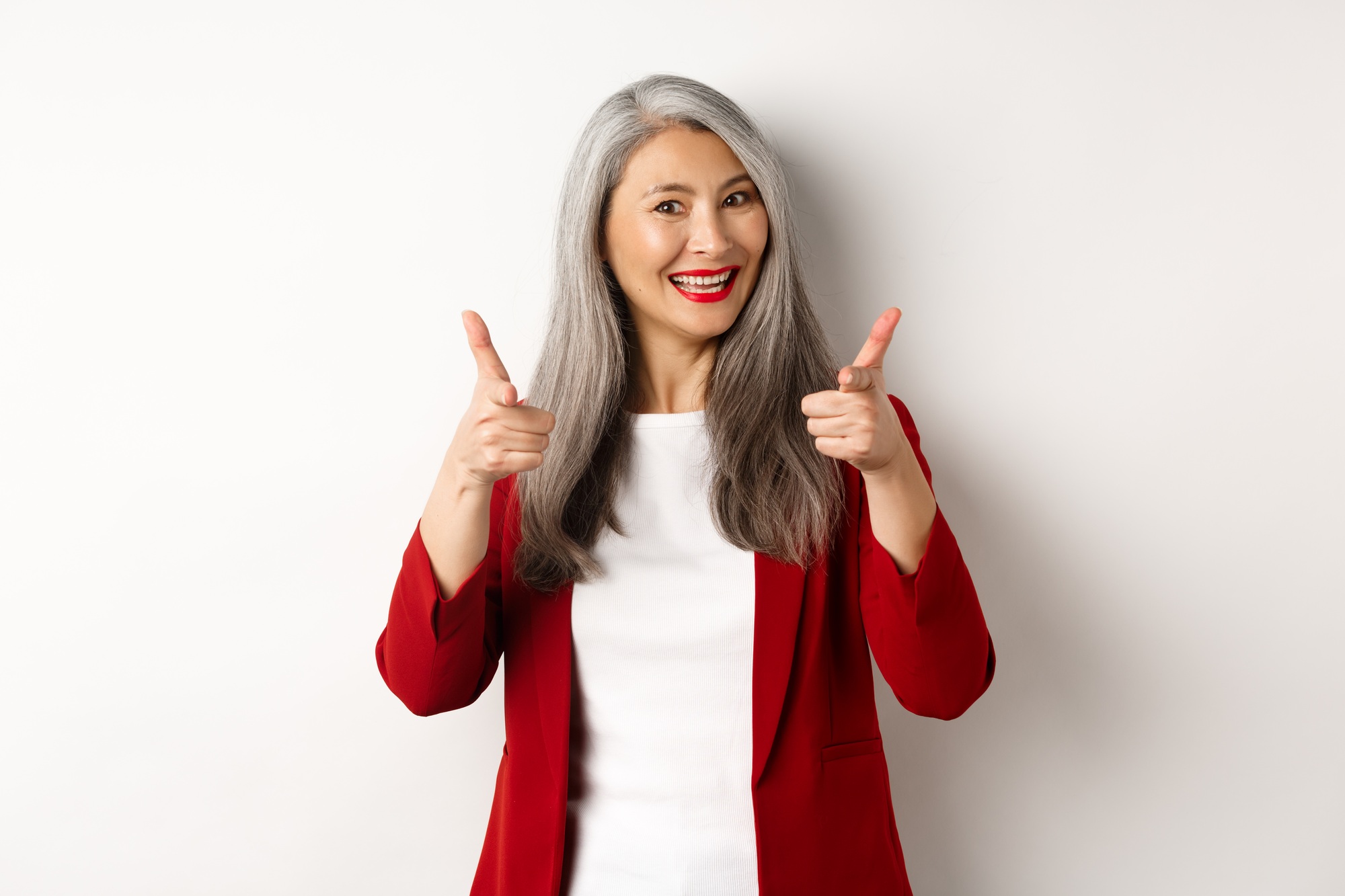 Professional female employer in trendy red blazer and makeup, pointing fingers at camera and smiling