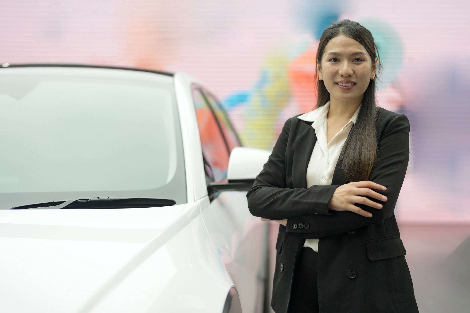 Professional woman standing confidently next to white car