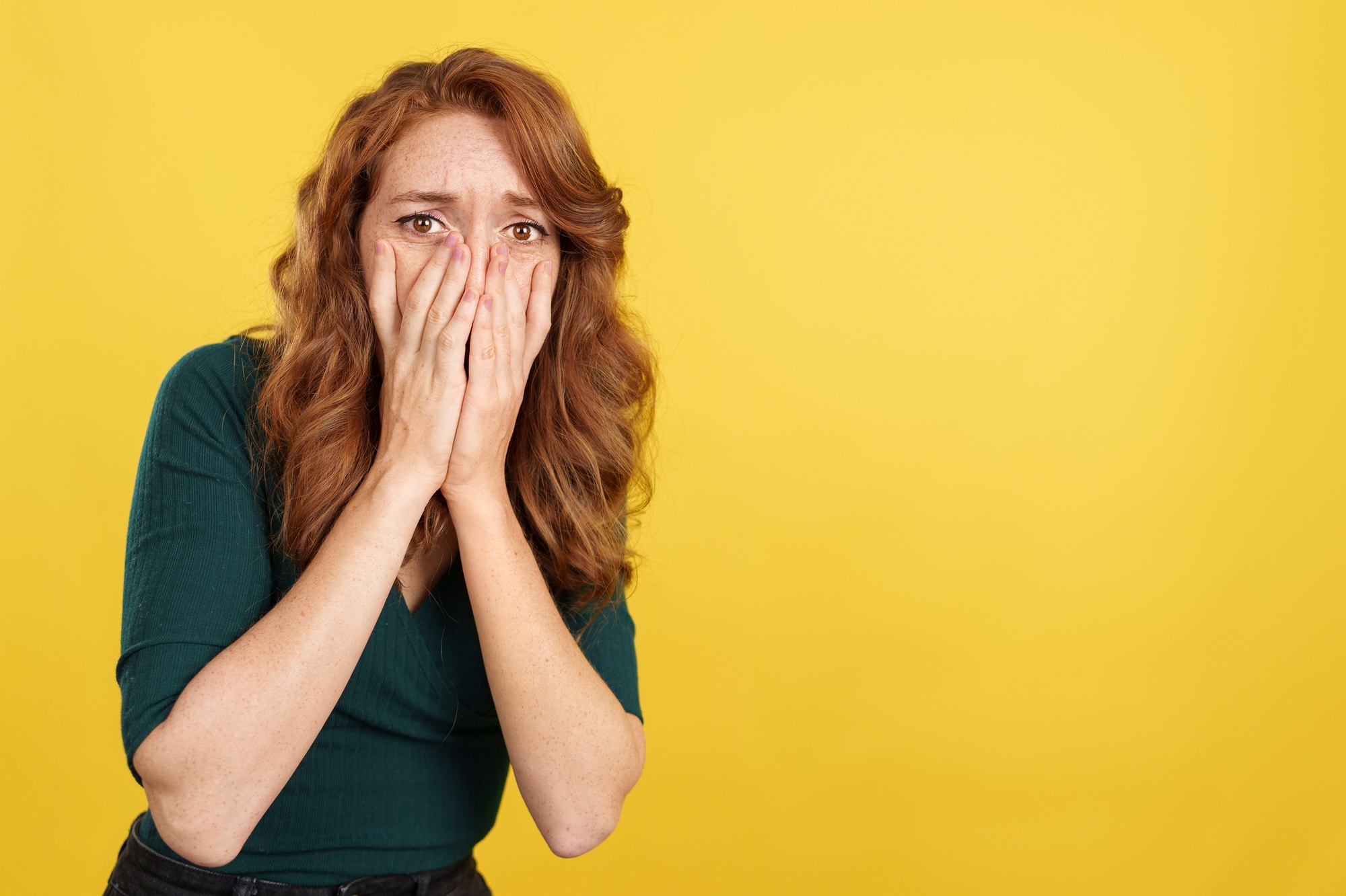 Redheaded woman covering the face in fear