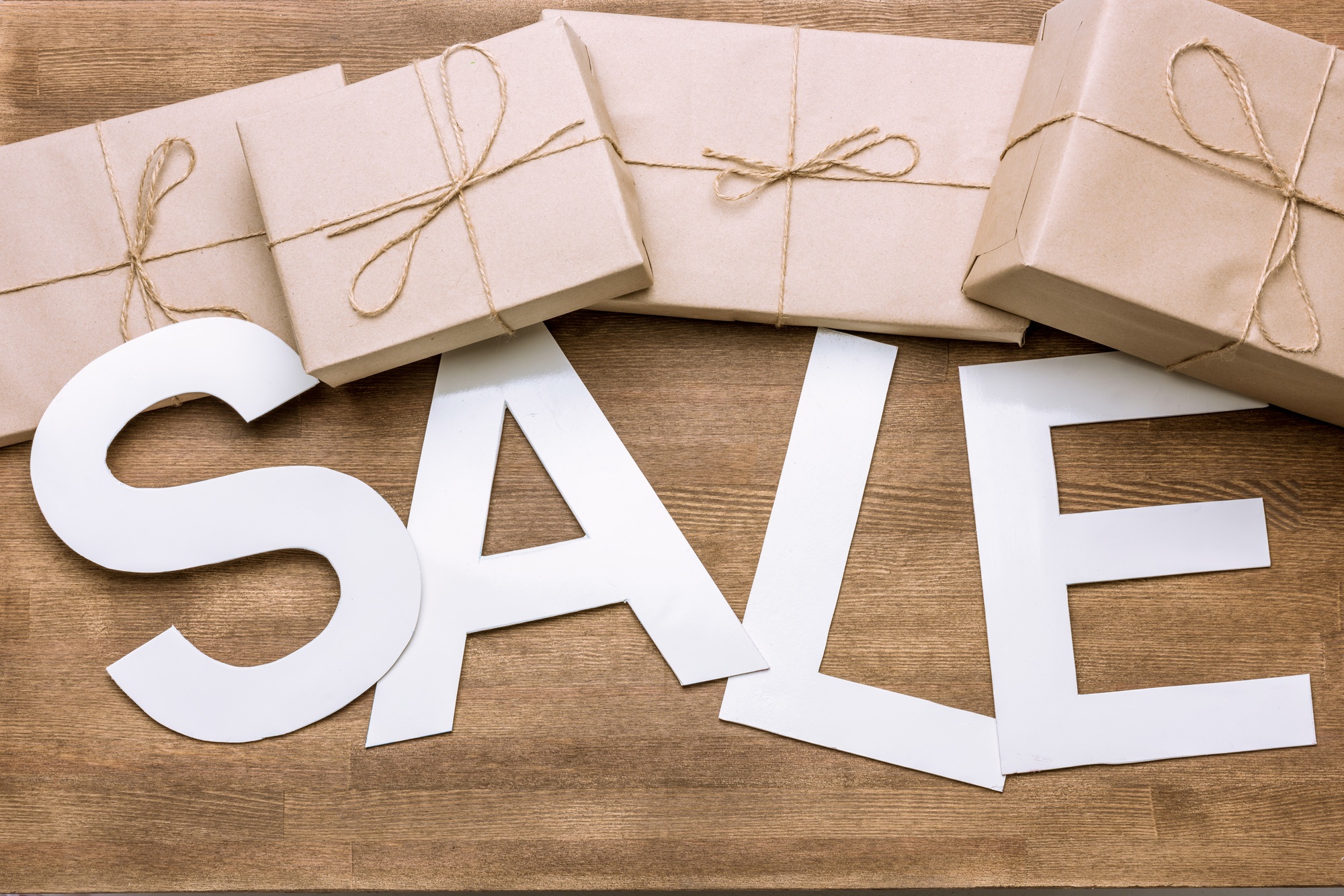 Sale sign with gift boxes on wooden surface