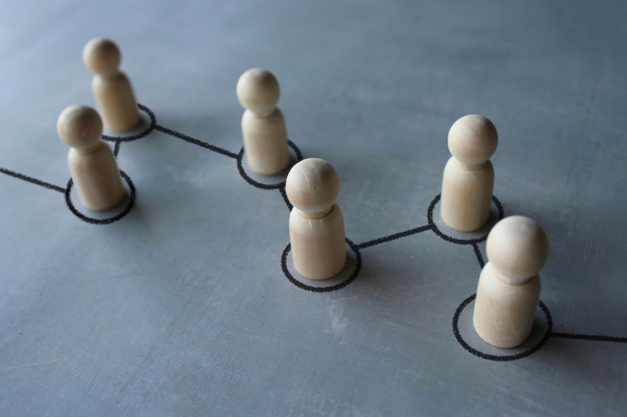 Selective focus image chain of wooden dolls connected by lines