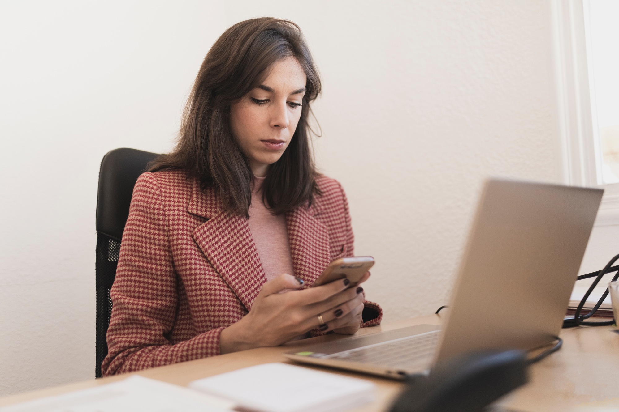 Serious woman with smartphone at workplace