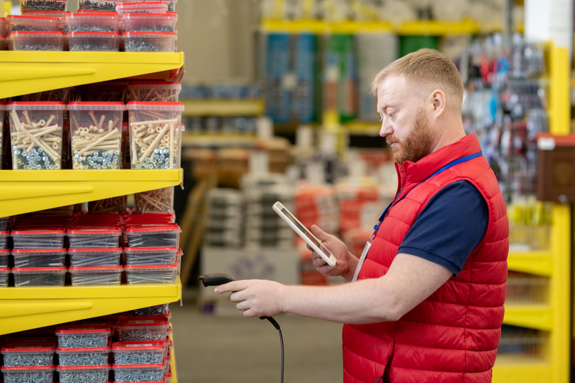 Shop assistant with tablet using scanner while checking prices