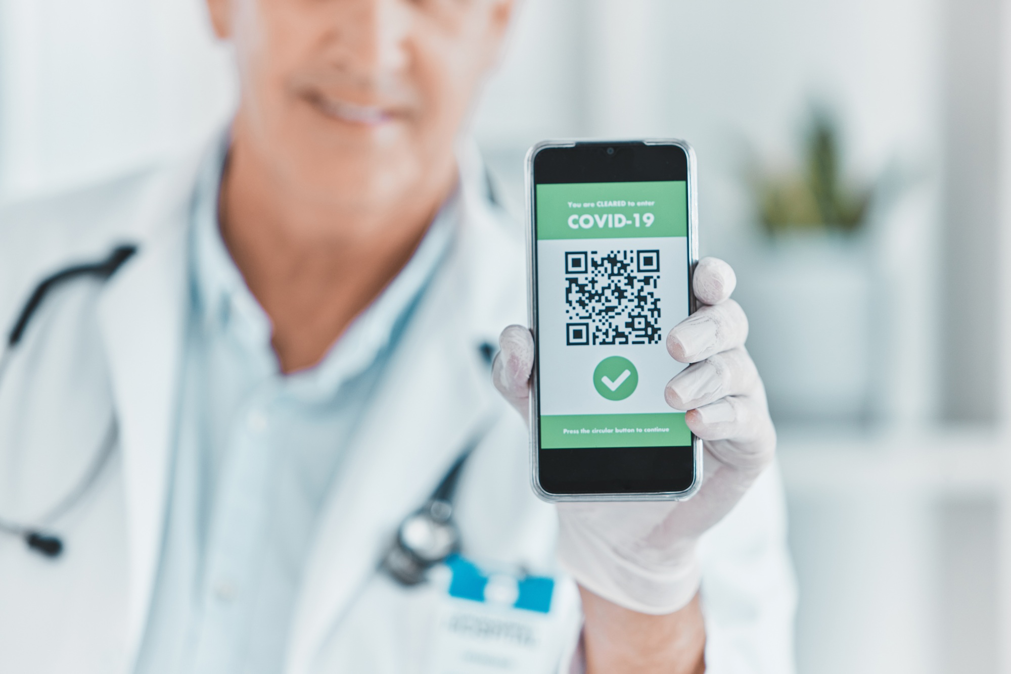 Shot of a male doctor holding a smartphone depicting a QR code to be scanned