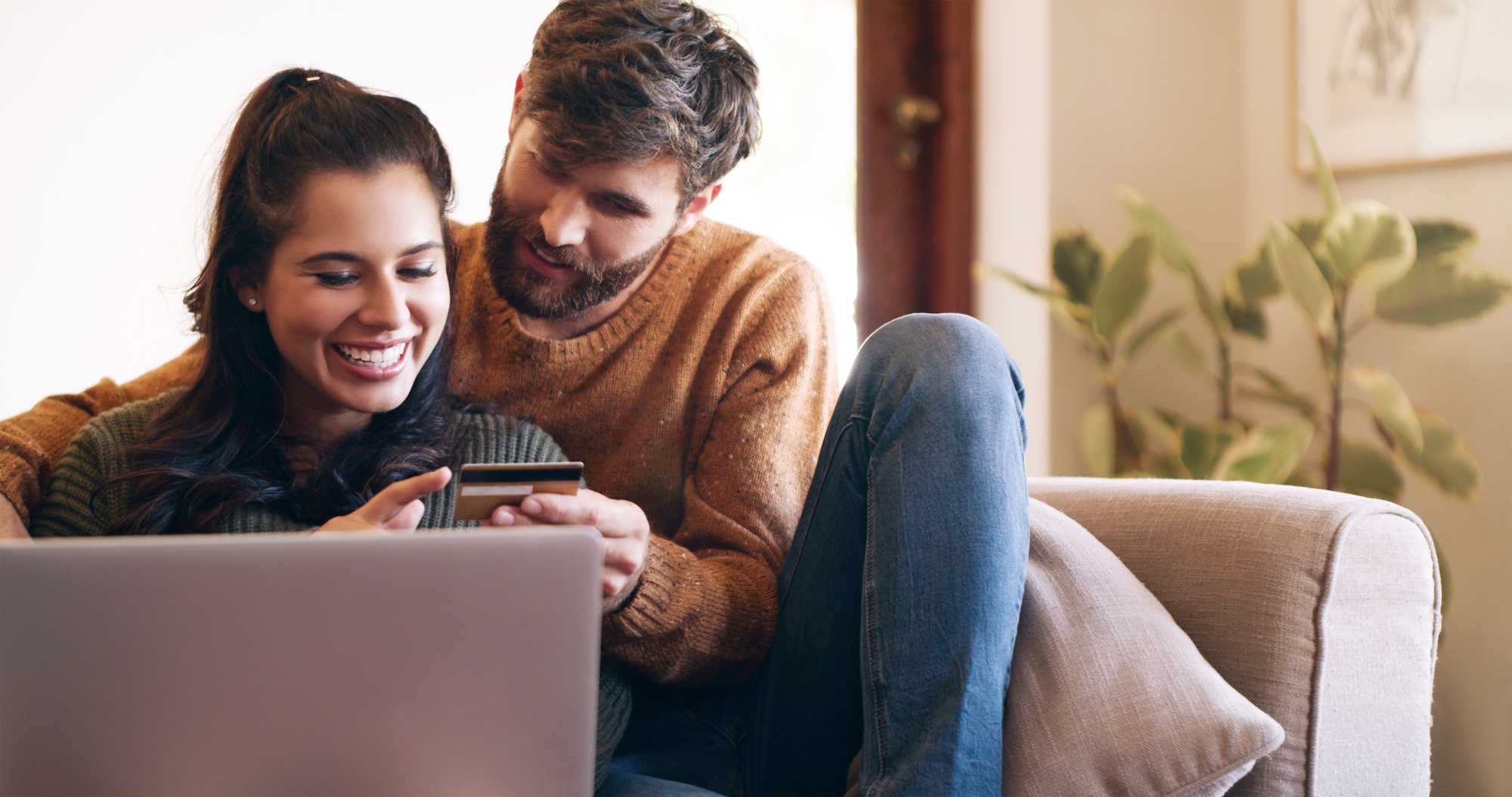 Shot of a young couple using a laptop and credit card on the sofa at home