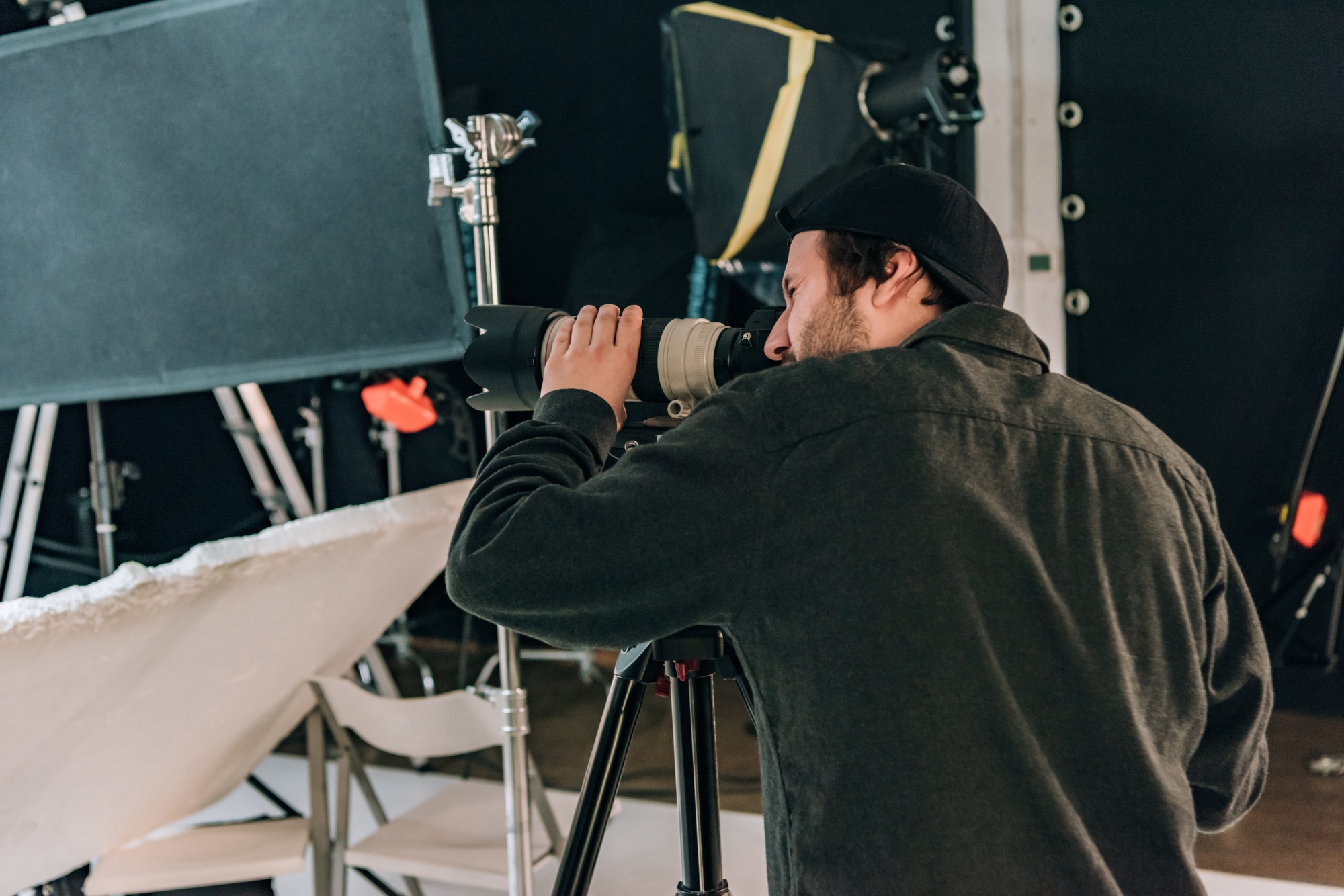 Side view of videographer with camera and reflectors at background