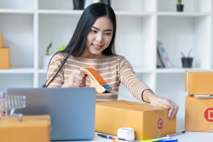 Small start-up business woman working with parcel boxes packing goods in preparation for delivery.