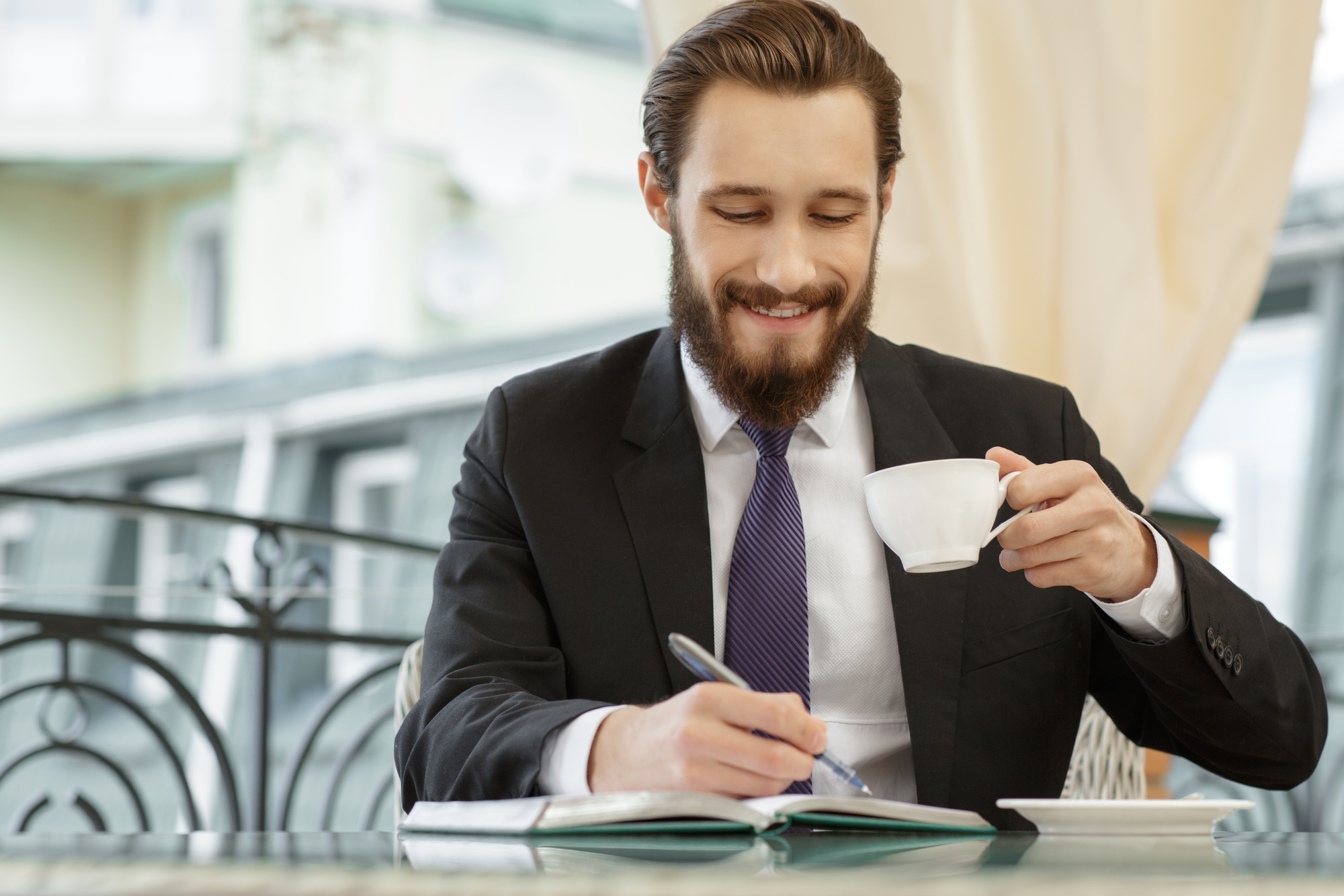 Smiling male executive writing to-do list during breakfast