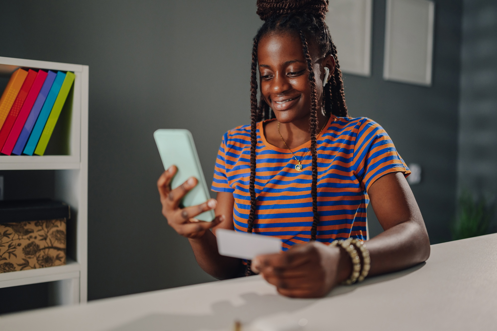 Smiling young woman making online payment using smartphone and credit card