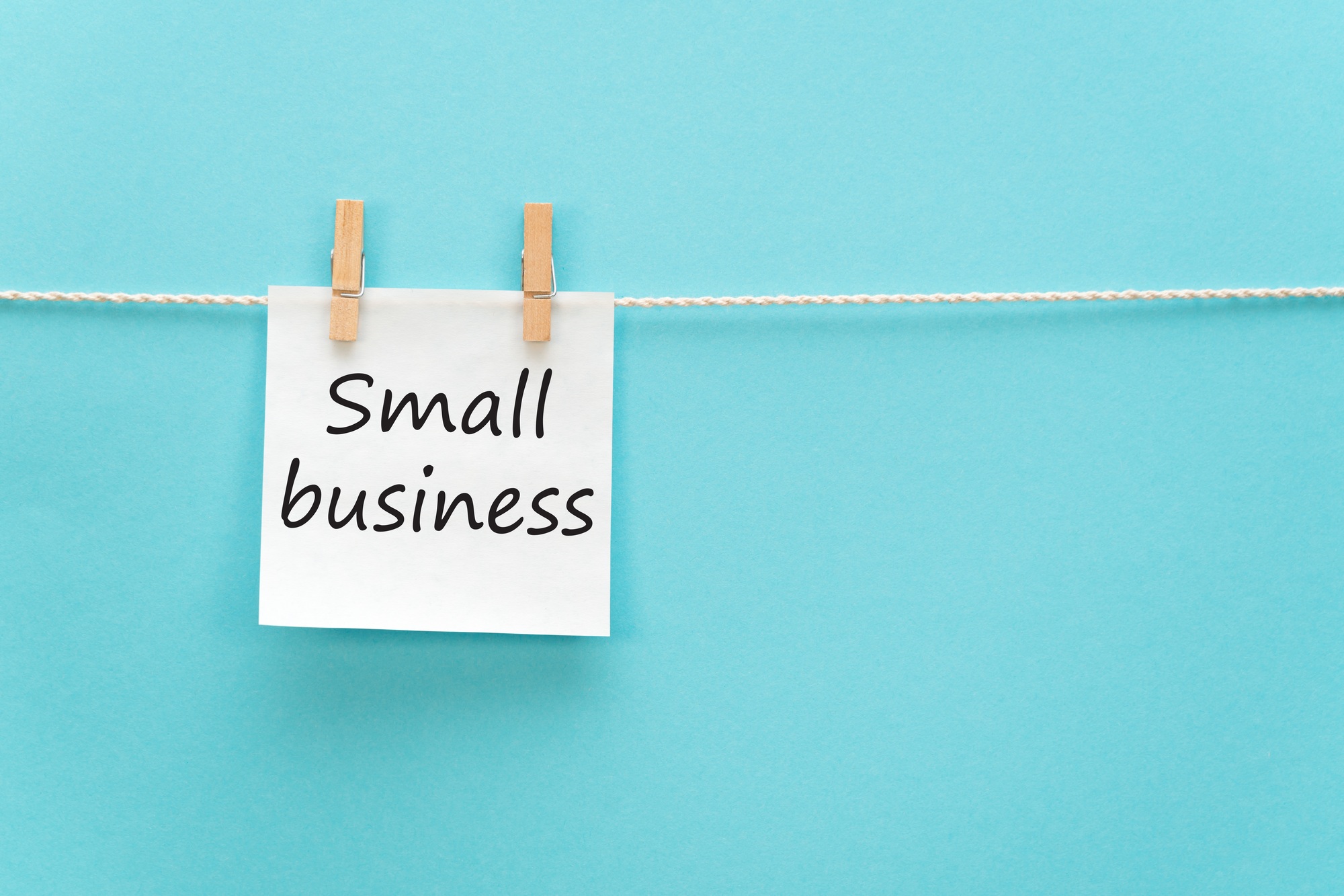 sticker with the inscription Small business hangs with a clothespin on a rope on a blue background
