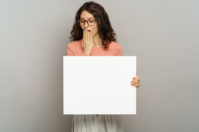 Surprised businesswoman hold placard with space for advertisement message, young female isolated