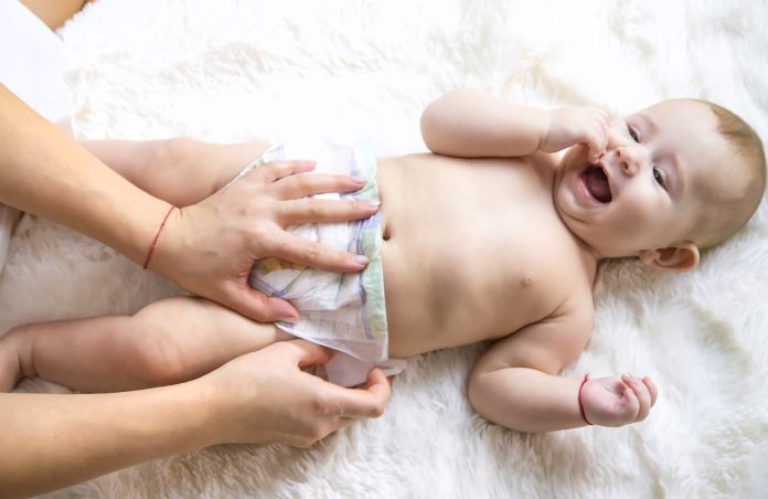 The mother is changing the baby diaper. Selective focus.