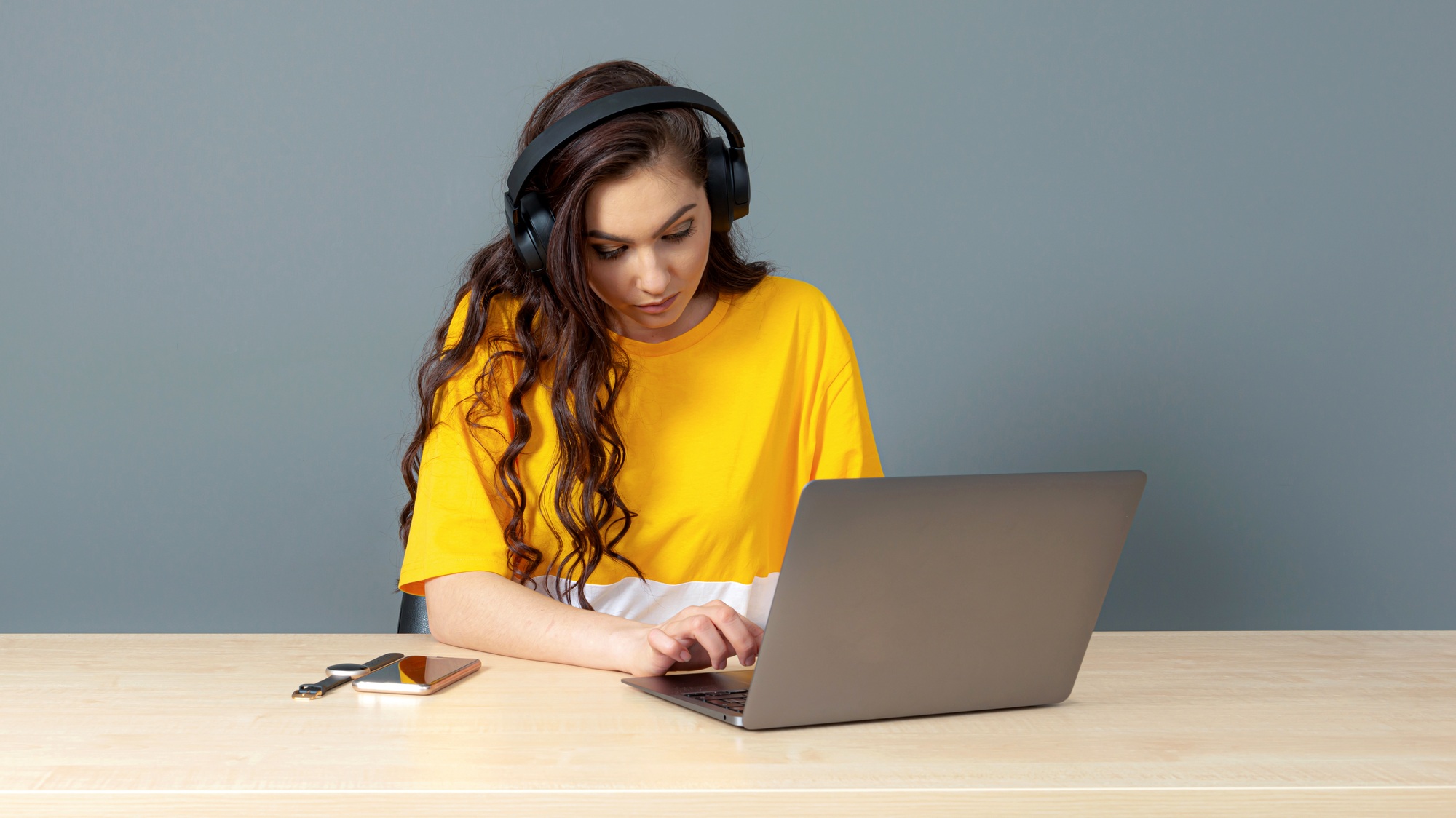 the student sits with a headset at the computer, watching and listening to video tutorials online