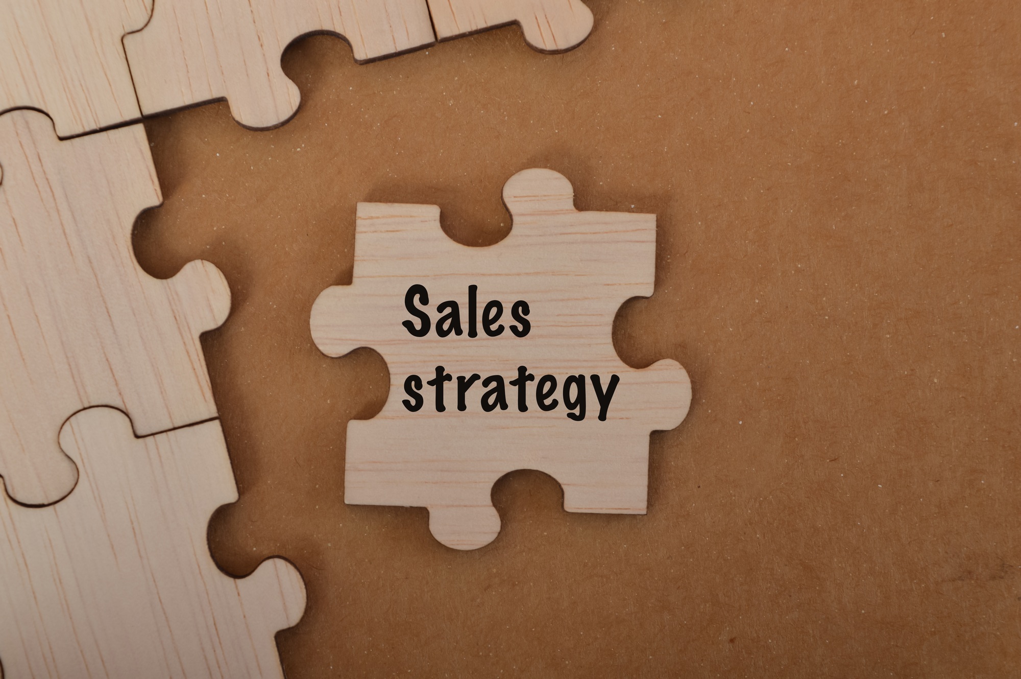 the word SALES STRATEGY is written on jigsaw puzzle.