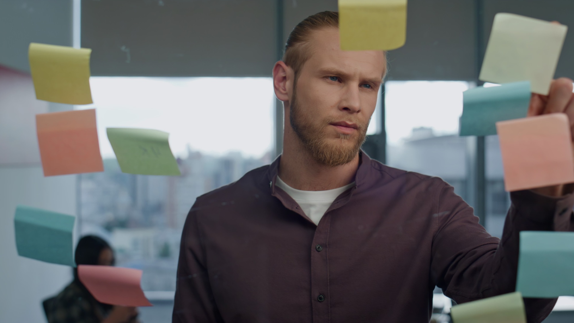 Thoughtful man pondering sticker wall office closeup. Startuper brainstorming