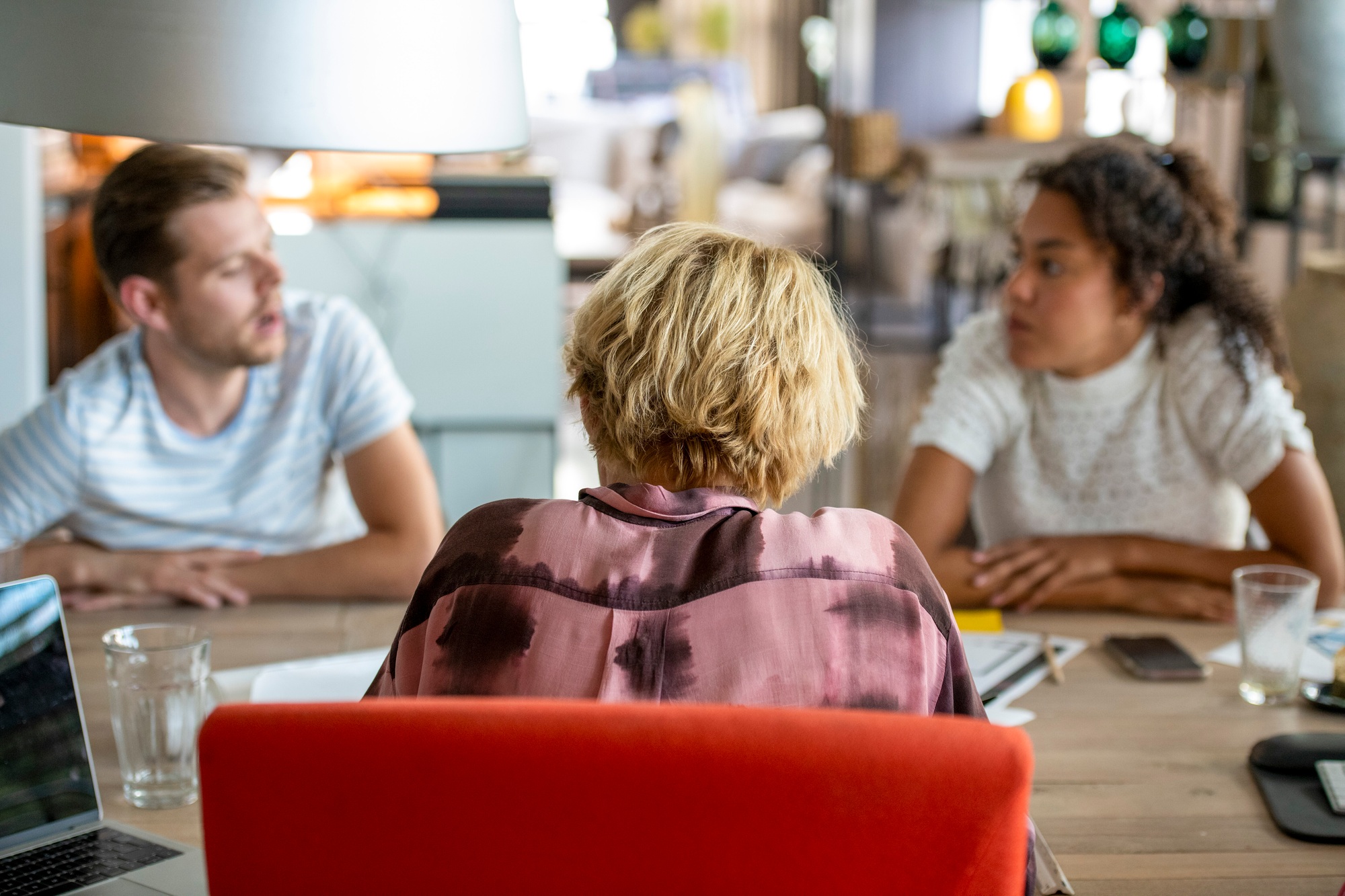 Three young adults engaged in a focused group discussion around a table.